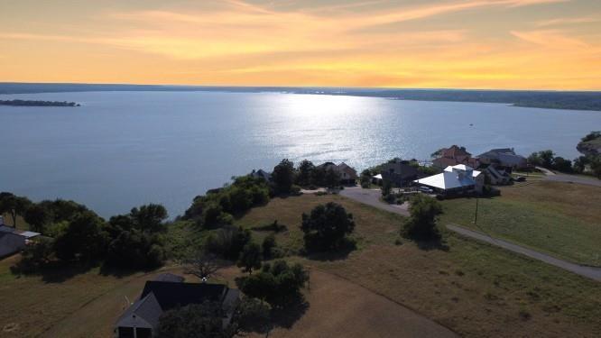 BEAUTIFUL VIEWS OF LAKE WHITNEY to the south and west. Located in a gated resort with two 18 HOLE GOLF COURSES, MARINA, 4 SWIMMING POOLS, restaurant, fitness center, tennis courts, playground & RV park. Seconds from marina and boat ramp on a beautiful, clear, blue water lake with some of the best fishing & water sports in Texas. Homesite is cleared with one large live oak tree in front yard. Perfect place to build a split level or one story home. Enjoy golfing, boating, swimming, deer, wildlife & the prettiest sunsets in Texas. Create your own staycation getaway and make memories to last a lifetime! Adjacent lot also available - 10072 Lakeview Court $145,900. For a total of .947 Acres
