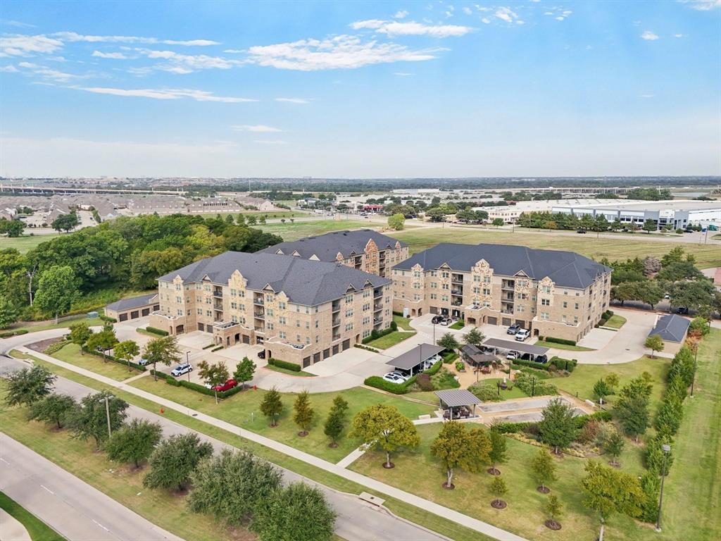 BEST OF CLASS!! Experience effortless living in this beautifully maintained LIKE NEW, TOP FLOOR CORNER CONDO in The Gatherings, a vibrant 55+ ACTIVE ADULT COMMUNITY in Mercer Crossing, Farmers Branch. Designed for a true LOCK & LEAVE LIFESTYLE, this low-maintenance residence lets you travel freely while everything at home is taken care of.  Enjoy peace of mind with COA managed exterior and grounds maintenance, plus a convenient concierge service that collects your trash & recycling right from your door. The community is thoughtfully designed for both relaxation & connection, featuring a fitness center, social spaces, bocce court, greenhouse, gardening areas, & outdoor cooking patio, all just steps away. Serene, park-like surroundings and a picturesque pecan grove complete the setting.  This spacious and popular 2,031sf Wiltshire plan offers penthouse views, 9ft ceilings, abundant natural light, & a quiet interior-facing location away from road noise. The private balcony overlooks a charming garden courtyard, & with only one shared wall, privacy is exceptional. Inside, you’ll find an open-concept living and dining area with rich hardwood flooring, a well-appointed kitchen with quartz countertops, stainless steel appliances, upgraded dishwasher, & ample storage. The primary suite features a large walk-in closet with enhanced shelving & a spa-like bath with dual sinks & a seated shower. The 2nd bedroom & bath provide comfort for residents or guests, while the 3rd bedroom can serve as a an office, hobby space, or private suite.  Additional highlights include in-unit laundry (washer & dryer included), upgraded storage throughout, CAT-5 wiring, a private detached garage, & move-in-ready condition with fresh paint & professionally cleaned flooring.  Optional access to Mercer Crossing amenities: pool, fitness center, dog park, & scenic trails adds even more appeal. With easy access to major highways, both airports, & downtown Dallas, this is carefree living at its best!