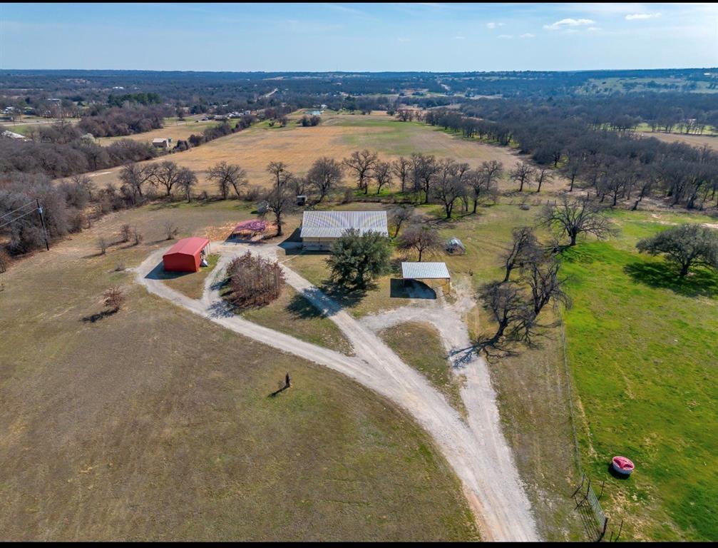 Experience the perfect blend of wide-open Texas skies and comfortable country living on this exceptional 17-acre ranch property. Tucked away for privacy yet convenient to town, this versatile estate offers room to roam, work, entertain, and unwind. The ranch-style home welcomes you with spacious living areas, abundant natural light, and a layout designed for both everyday living and gatherings with family and friends. Whether you’re enjoying quiet mornings on the porch or hosting lively weekends, this home delivers warmth and functionality. Outdoors, the possibilities are endless. A large shop provides ample space for projects, equipment, or business use, while the guest house offers ideal accommodations for extended family, visitors, or rental potential. Multiple carports ensure covered parking for vehicles, trailers, or recreational toys, and an additional storage building keeps everything organized. Two water wells add valuable self-sufficiency, supporting the home, land, and livestock with ease. The scenic pond enhances the natural beauty of the acreage, creating a peaceful setting for fishing, relaxing, or simply enjoying the view. Whether you envision a working ranch, a private retreat, or a multi-generational homestead, this rare 17-acre property offers the freedom and flexibility to make it your own. Inside the home is a nicely concealed category 4 storm-tornado shelter for added safety.