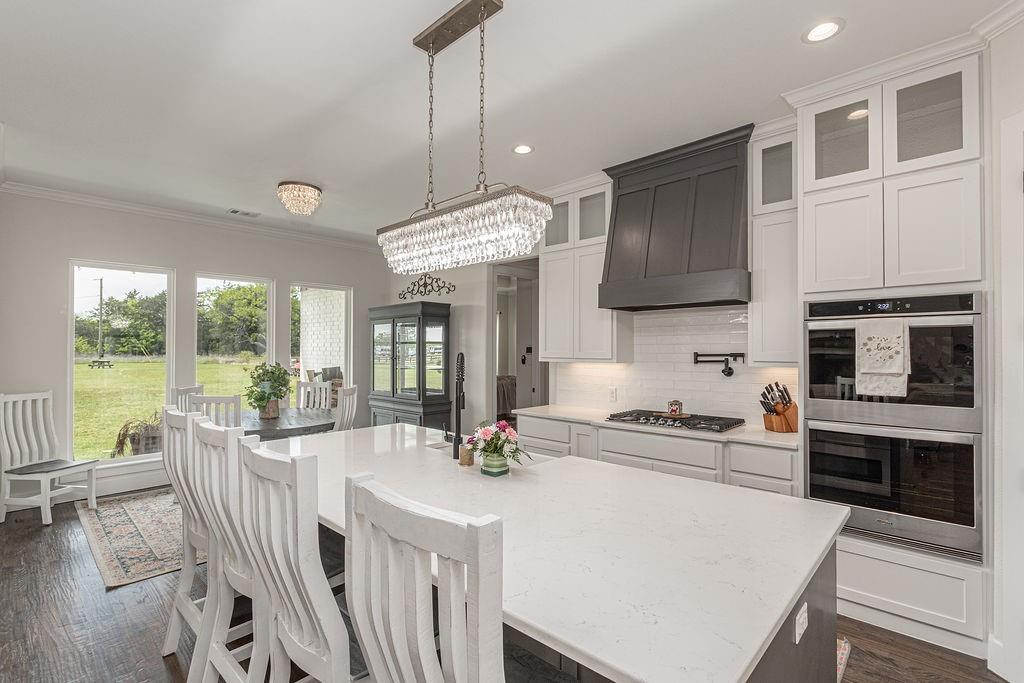 Custom built in 2022, this stunning 4 bedroom, 4 bath (plus a bonus toilet and sink in shop) home sits on approximately 4.9 fully fenced acres with a pond, offering the perfect blend of modern design and peaceful country living. Spanning almost 3000 square feet, the home features an open and airy layout with rich wood flooring, abundant natural light, and a dedicated office. The spacious living area is anchored by a brick fireplace and flows seamlessly into a beautifully designed kitchen with extensive cabinetry, generous counter space and a large island ideal for gathering and entertaining. Exceptional storage can be found throughout the home, along with added insulation for enhanced energy efficiency in both the home and garage. The private primary suite offers a relaxing retreat with serene views of the property, while secondary bedrooms are well sized and thoughtfully positioned with en suite bathrooms. Step outside to enjoy your large back porch with exterior fireplace, wide open views, and plenty of room to expand, entertain, or simply unwind. The 30 x 40 shop is fully equipped with 100 amp electric, a separate pump system servicing a toilet and sink, a 25 foot overhang in the front, and a 15 foot extension in the back, making it ideal for work, storage, or hobbies. The property also features a 50 amp RV hookup with dedicated pad and footings for a future porch, along with water, electric, and septic already in place. This property offers a great combination of newer construction, functional land, and versatile improvements, all in a highly desirable location.