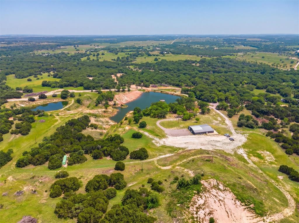 550 Manley Lane, Weatherford, Texas. 25 Acres of Texas Hill Country Perfection This exceptional 25 acre ranch offers rolling topography, mature scattered oak trees, and breathtaking panoramic views sweeping to the southwest. Nestled among large neighboring ranches, the property delivers true privacy and the classic Texas ranch lifestyle. A highlight of the property is the brand new 2-acre pond (constructed last year), which reaches 25 feet deep. Professionally stocked with bass and crappie and fed daily, this lake is primed to produce trophy bass in the coming seasons. A large custom built dock extends over the water, creating an outstanding fishing and recreation spot for family and friends. The centerpiece of the ranch is the impressive 80' x 60' barndo with 1,930 sq ft of comfortable living quarters. The living area features a spacious, open great room, custom cabinetry, and beautiful granite countertops throughout. The layout includes 1 bedroom and 1 full bathroom, plus multiple additional rooms ideal for a home office, guest space, or future expansion. Two fully insulated interior shop areas (40' x 30' and 15' x 80') provide outstanding workspace and storage. Utilities are well established with two water wells, one dedicated to the barn-living quarters and the second for general ranch use. The barndo is move-in ready, making it perfect for weekend getaways, immediate full-time living, or as comfortable quarters while you build your dream home on the elevated hill just behind the shop. That hilltop building site boasts million-dollar southwest views that stretch for miles. Whether you're looking for a turnkey weekend retreat, a private fishing haven, or the ideal spot to develop your custom Texas ranch estate, 550 Manley Lane delivers it all. Prime location, productive land, water features, and endless potential, this property is a rare find in the Weatherford area.