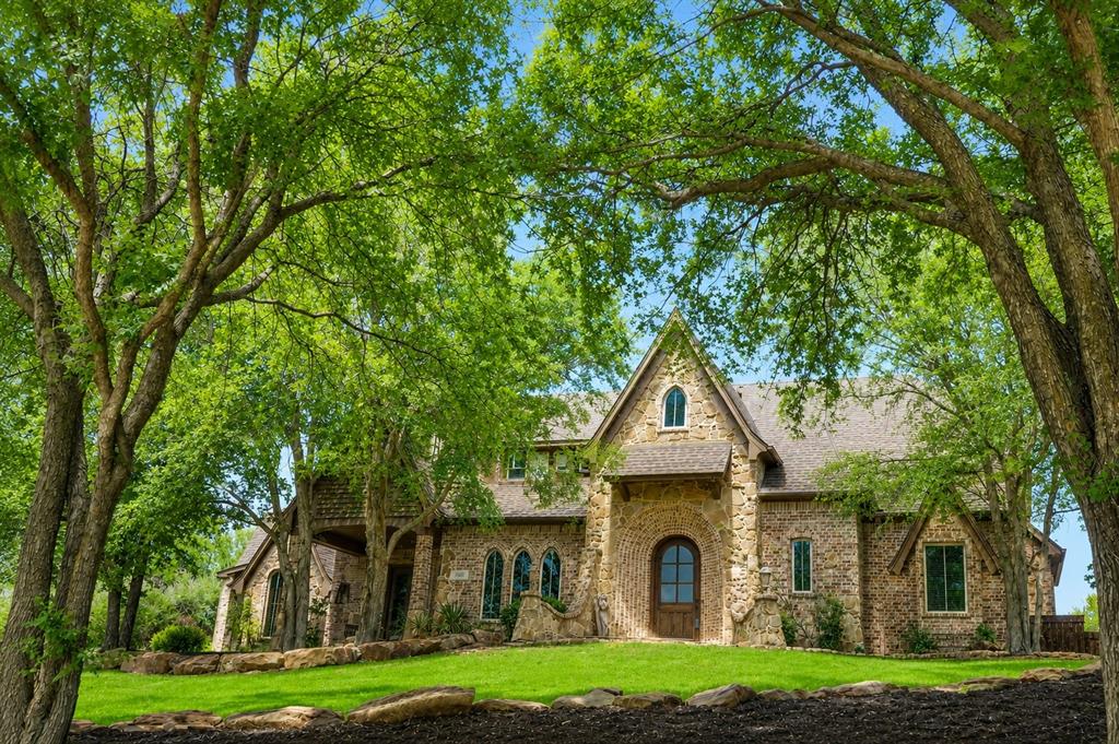 Stunning 5,000 plus sq ft European-inspired estate nestled on a private 1 plus acre tree-lined lot in the exclusive gated community of Forest Hills. This custom home showcases timeless Old World architecture with stone accents, rich wood finishes, and exceptional craftsmanship throughout.
Designed for both everyday living and entertaining, the chef’s kitchen features built-in double ovens, oversized island, custom cabinetry, designated wine room, and seamless flow into the living and dining areas. The spacious living room boasts soaring vaulted ceilings with exposed beams, a floor-to-ceiling stone fireplace, expansive windows overlooking the resort-style backyard, and electric blinds in both the living and kitchen dining areas for added comfort and convenience.
Step outside to your private oasis complete with a sparkling pool, waterfall, grotto, tanning ledge, spa, and multiple entertaining areas including a covered patio, natural gas built-in outdoor grill, and fire pit. Separate fenced areas provide added flexibility for pets, play, or private outdoor spaces.
The flexible floor plan includes a luxurious primary suite with spa-like bath, large secondary bedrooms, game room, media room, and a private office with custom built-ins. A separate in-law suite with private entrance, kitchenette, full bath, and living space is ideal for multi-generational living or guests.
Additional features include a grand foyer with curved staircase and Juliet balcony, 3 car garage with 2 attached and 1 detached spaces, and extensive outdoor living areas. Conveniently located near Hwy 380 and the Dallas North Tollway with easy access to shopping, dining, and top-rated schools.