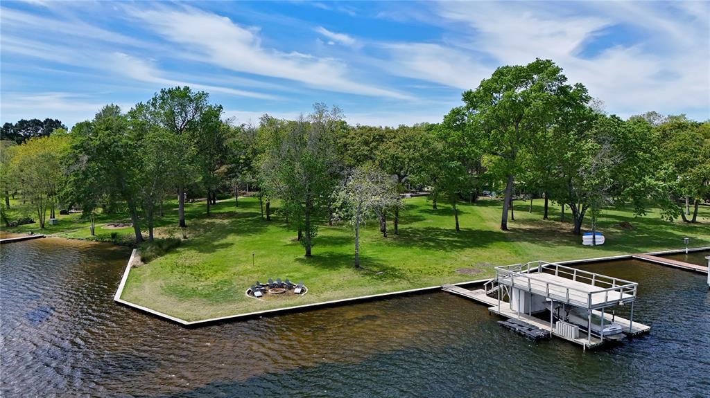 This stunning lakefront estate offers the ultimate in comfort, space, and waterfront living. Featuring 5 bedrooms and 4 bathrooms across 3,994 sq. ft., the home boasts approximately 250 feet of shoreline in a quiet, low-traffic area near the Lake Athens dam—providing privacy and breathtaking views. Designed for both everyday living and entertaining, the open-concept living room flows seamlessly into the kitchen, complete with granite countertops, a pantry, and electric appliances. A separate sitting room with a fireplace showcases beautiful lake views, while abundant storage and closet space are found throughout the home. Two private primary suites—each with walk-in closets and en-suite baths—offer flexibility for guests or multi-generational living. Outdoor living is just as impressive, with a covered back porch, fire pit by the water, and incredible views from nearly every angle. The two-story boat dock includes a boat lift and ample seating, making it ideal for entertaining family and friends. Additional features include a loft area perfect for a second living space or bunk room, a spacious utility room, a large two-car garage, and a new retaining wall completed in 2024. Perfect for large families, hosting unforgettable gatherings, or simply enjoying peaceful lake life, this exceptional property delivers luxury, privacy, and unforgettable waterfront experiences.