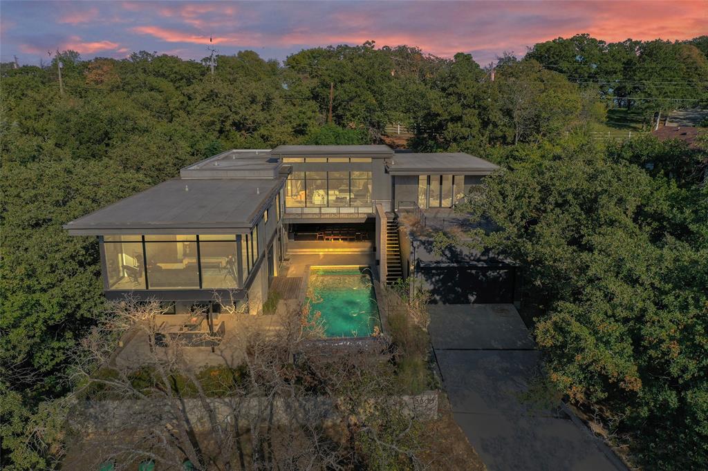 Modern luxury custom home by RGD+B with stunning views! Expansive glass walls fill the space with natural light, giving the feeling of living in the treetops. The open living area offers sunset views, an electric fireplace, and flows into the dining and sleek kitchen with high-end cabinets, stainless appliances, oversized fridge, and large island with cooktop and seating. Light wood floors, tall ceilings, and built-in speakers add elegance. The primary suite overlooks Grapevine Lake with electric shades and a spa-like bath featuring dual sinks, glass shower, and large closet. Office and workout room or 5th bedroom open to balconies. Downstairs includes two bedrooms with private baths and a game room with sliding doors to the heated saltwater infinity pool, waterfall, and covered patio with outdoor kitchen and 4 hole putting green. Guest suite has private entry and bath. Oversized garage with great storage. A must see, check out the 3D tour!

---