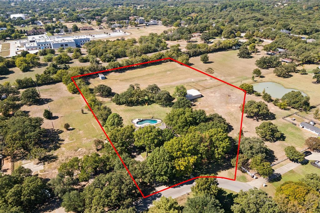 Welcome to 146 Jellico Circle, Southlake – a rare opportunity to own an expansive 4.98-acre property that promises both tranquility and space in a sought-after location. This unique offering consists of two sprawling parcels being sold as one property, providing ample room for those who appreciate outdoor living and privacy, all while backing to a charming almost 15 acre park with walking trail and playground. The property is highlighted by its mature trees and vast open spaces, perfect for gardening enthusiasts, those looking to create a play area or anyone who simply wants to enjoy the serene natural surroundings. Adding to its functionality and rustic charm, the acreage includes a 6-stall barn with tack room, a feed room, a loafing shed, fenced and cross fenced with pipe fencing, and has an area for lighted arena, ideal for horse lovers or those in need of additional storage. Step inside to discover a thoughtfully designed living space encompassing 3,335 square feet. This one story home with a 3 car garage features 4 spacious bedrooms and 3 full baths, 2 living areas, a large galley-style kitchen w breakfast area, & a formal dining room offering ample room for comfort & relaxation. The generous living areas are perfect for hosting gatherings or enjoying cozy family nights. From the covered patio, take in the view of the sparkling diving pool & spa – an ideal setting for entertaining throughout the seasons. Whether you choose to renovate the existing home, expand it, or build your custom dream residence, this property provides endless possibilities. Its peaceful setting coupled w abundant amenities makes it a unique find. Don’t miss the chance to seize this rare opportunity to own a piece of Southlake’s serene landscape where you can enjoy the perfect blend of privacy, nature & community all while being conveniently located close to Southlake Town Square, Keller Town Center & 15 minutes from DFW Airport w Southlake Carroll ISD Open Enrollment & Keller ISD schools.