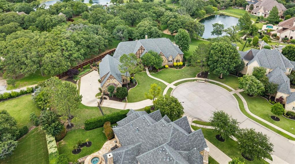 Set on nearly an acre at the end of a cul-de-sac, this single story estate in the gated enclave of Castleton Manor offers a rare blend of privacy, elegance, and resort-style living. Expansive outdoor living spaces overlook serene pond and park views! A fully equipped outdoor kitchen featuring a cooktop, refrigerator, sink, and ample storage is anchored by a heated diving pool with an automatic cover, beautifully remodeled by Claffey Pools. A five-hole putting green with a mini tee box adds a distinctive recreational touch. The property enjoys direct gated access to the community pond, park, and playground! Inside, soaring 12-15 ft ceilings and rich 5 inch walnut flooring define the home’s refined interior. The private primary suite is a true retreat, complete with a spa-inspired bath featuring an 8-foot Bain Ultra jetted tub, Kohler shower system with body jets, an in-bath refrigerator, and a reinforced steel safe room discreetly integrated into the custom closet. Each bedroom is thoughtfully designed with its own en suite bath. The chef’s kitchen is both functional and sophisticated, appointed with Alderwood cabinetry, a large walk-in pantry, dual ASKO dishwashers, a Viking Professional six-burner gas range, Thermador refrigerator and freezer columns, GE Monogram convection oven-microwave, and a Wine Captain. Entertaining continues in the spacious gameroom with a wet bar & beverage fridge, and a designated Music Room. A richly appointed wood-paneled office showcases coffered ceilings, a fireplace, and custom built-ins, while energy-efficient Pella windows and doors and a radiant barrier enhance comfort throughout the home. Car enthusiasts will appreciate the 4 car garage, gated driveway, and storage rooms. Above the garage, a generous living area with a full bath, wet bar, and built-ins offers flexible use! Located just minutes from the DFW International Airport. Nearby Southlake Town Square and Downtown Historic Grapevine offer endless shopping and dining options!