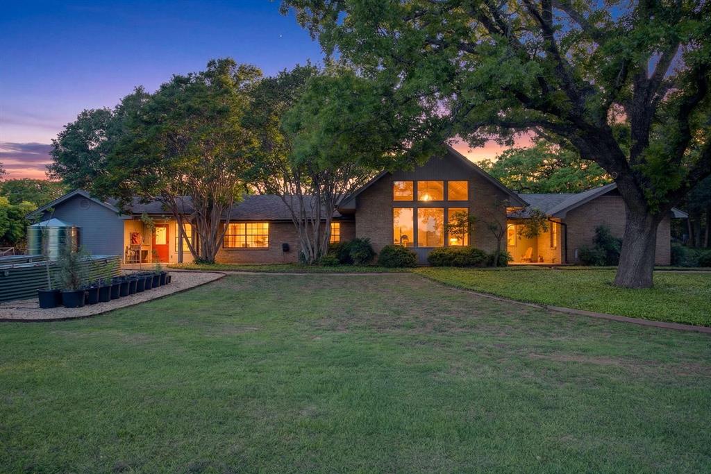 BACK ON MARKET: NO FAULT OF THE HOME! Buyers did not sell their house. Extraordinary opportunity to own a homesteader's dream in the countryside of Burleson, Texas! Over 5 acres of remarkable land: shade trees, lush pasture, perimeter fencing, and the character you hope for in details like a windmill, a rosemary-lined chicken yard, and a seasonal creek bed. The residence sits shaded and private with multiple porch and patio spaces for intimate moments as well as large gatherings - most notably the expansive upper deck above the parking area connected to the interior's loft and the covered, enclosed patio below that begs to make al fresco dining a nightly occurrence. The interior boasts a smart and stylish fusion of bold, modern finishes with rustic, primitive flair cherished in this kind of home. The kitchen was blown wide open while maintaining the brick-laid flooring that runs throughout the common spaces; the living area enjoys stunning tree-ensconced views through massive windows up to the wood-paneled vaulted ceiling. The grand wood pellet brick fireplace naturally centers the home. Secondary bedrooms enjoy personality and a fun full bathroom opposite the sumptuously scaled primary suite with a surprisingly large walk-in closet and laundry area. Don't miss the dreamy loft or the charming pantry screen door. New LED recessed lighting, ceiling fans, fixtures and paint modernize each space. Outside: a 1600+ gallon water cistern irrigates raised metal garden beds prepped with fill; the two car garage with awning hides a huge 'bonus space' perfect for a gym or home office (on its own meter, too); the 24x24 open pole barn is your catch-all; more storage and opportunity awaits in yet another 24x24 workshop. Roof replaced 2024 with guarded gutters; Lennox dual-zoned HVAC in 2025; extra exterior outlets installed; mounted, retractable hoses. And available to you: the master plan commissioned for the home and the land. Already exceptional with untapped potential.