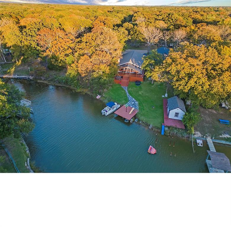 WATERFRONT SHORT-TERM RENTAL OR PRIVATE RESIDENCE.  This inviting large FULLY FURNISHED home sits serenely on the calm waters of a winding lazy channel leading to open water. Designed for flexibility of use, the Open Plan consists of 4 Bedrooms, 2 of which are Primaries with ensuites, plus 2 Flex Rooms for even more sleeping space.  4 Full Bathrooms provide plenty of privacy and 4 mini-split units allow individualized temperature settings in each Bedroom. The Open Living-Dining-Kitchen will fill your dreams with beautiful views of the lake while you entertain or cozy up to the wood burning fireplace.  The chef's Kitchen has it all, from a large Island, granite countertops, lots of cabinets, wine fridge, ice maker, walk-in pantry and more. Guests can gather at the Kitchen Island or enjoy the Dining Area overlooking the lake. Glass doors in the beautiful wall of windows open to an expansive covered deck where you can enjoy your morning with nature or unwind at the end of the day in the bubbling hot tub. A natural stone path leads to the waters' edge and your private fishing dock.  Bring your water toys and launch from 2 nearby community boat launches or go for a dip in the community pool. There is so much to enjoy at this waterfront piece of beautiful Texas and it proves true the adage, LIFE IS BETTER AT THE LAKE! Furnished, move-in-ready and NOW is the SEASON TO BUY. Grab this opportunity and enjoy your summer of relaxation or the income from your short-term rental.  Beautiful Cedar Creek Lake is 1 hour southeast of Dallas with great restaurants, shopping, medical facilities and community events to enjoy.   EVERYTHING is better AT THE LAKE!