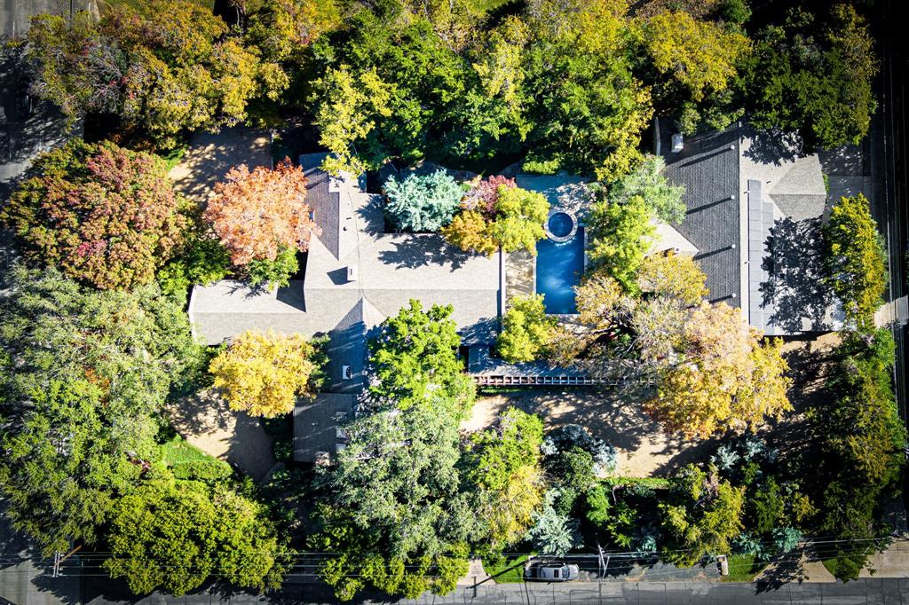 Indulge in timeless elegance at this extraordinary estate, once the home of renowned designer Robert (Bobby) Turner. Nestled on a sprawling 0.97-acre lot, this secluded property offers over 6,500 square feet of meticulously designed living space. Escape the hustle and bustle of city living as you enter through a gated porte-cochere and into a magnificent entry foyer with floor-to-ceiling windows. The gourmet kitchen, perfect for culinary enthusiasts, features top-of-the-line appliances, a center island, breakfast bar, and butler's pantry. Spacious living areas with vaulted ceilings and breathtaking views of the backyard oasis create a serene atmosphere. The primary suite is a true retreat, offering a sitting area, fireplace, dual vanities, an oversized custom walk-in closet, and a spa-like bathroom. A private 2,237-square-foot guest house with two bedrooms, two bathrooms, a living area, kitchen, and laundry room provides ample space for guests. The backyard oasis is a true paradise, featuring a sparkling pool, a charming pavilion, a cozy fireplace, a serene man-made stream, a picturesque bridge, and lush landscaping. Experience the epitome of luxury living in this exclusive Old Preston Hollow estate.