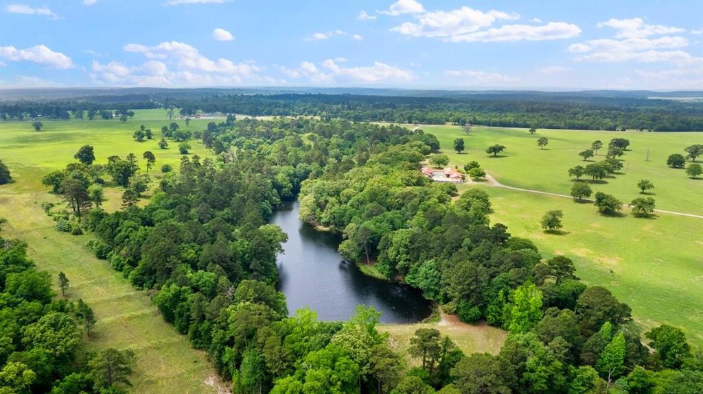 Positioned equidistant from Quitman, Winnsboro, and Gilmer, this 348±-acre legacy ranch stands as one of East Texas’ rare offerings—where luxury living, natural beauty, and exceptional land stewardship converge. The landscape unfolds in a striking blend of rolling pastureland, mature hardwoods, and a serene spring-fed lake, creating a setting that is both visually captivating and remarkably functional.

At the heart of the property, a 5,037 sq ft Mediterranean-style main residence commands the terrain with timeless presence. Thoughtfully designed around a private courtyard, the home features a sparkling pool and an independent one-bedroom guesthouse, offering privacy and comfort for guests or extended stays.

A separate 1,167 sq ft two-bedroom guest house provides additional accommodations, while a 3,200 sq ft metal barn delivers substantial space for equipment, storage, or ranch operations—ideal for both recreational and working-ranch pursuits.

A long, picturesque driveway winds through pastures of coastal bermuda grass perfectly suited for grazing or hay production. Beyond the open fields, the wooded acreage invites abundant wildlife, premier hunting opportunities, and endless outdoor recreation. Every element of the land has been curated to balance beauty with purpose.

Nestled just below the main home, the spring-fed lake serves as a signature focal point. Complete with a charming fishing dock, the lake’s continuous overflow—fed by robust natural springs—demonstrates impressive water volume and signals the potential for expansion or the creation of additional water features.  Additional springs originate and feed creeks that run throughout the property. 

The ranch offers dual frontage on both N FM 2869 and E State Hwy 154, providing exceptional access, visibility, and long-term versatility.

All due diligence and information to be verified by the buyer.