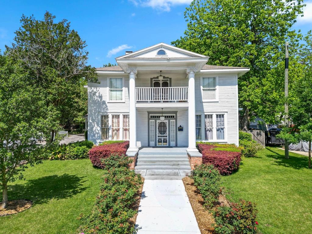 Steeped in history and quiet grandeur, the John M. Holman House, built in 1913, stands as one of Pittsburg’s enduring treasures within it's Historic District. Featured in books and films, this 4,758 square foot residence offers 8 bedrooms and 6.5 baths on a beautifully kept .37 acre lot, where every space tells a story.

A plaque at the front hints at its legacy, while the columned porch invites you into a home rich with character. Inside, original pine hardwood floors, soaring ceilings, intricate millwork, and soft, timeless lighting create an atmosphere that feels both elevated and warmly lived in. The grand staircase, adorned with quaint stair runners, leads you upward past the preserved tapestry in the hallway, a rare and beautiful nod to the home’s past.

The main level unfolds much like it would have over a century ago, with a gracious parlor and sitting room anchored by wood burning fireplaces, a formal dining room made for gathering, a quiet study, and multiple living spaces that invite conversation and connection. Upstairs, a light filled common area opens to a balcony, offering a peaceful place to pause.

With six bedrooms upstairs and two downstairs, the home offers flexibility and charm in equal measure. Four bathrooms are located upstairs, with two full baths and a half bath downstairs. Many of the bedrooms enjoy private or adjoining bath access, and two rooms serve as intimate sitting areas connected to adjoining bedrooms, once used as a private suites during its time as a bed and breakfast. The half bath can be found tucked discreetly beneath the staircase.

The kitchen blends timeless character with modern convenience, featuring marble countertops, custom cabinetry, a gas range, and stainless appliances. Thoughtful infrastructure updates, including HVAC, water heaters, 200 AMP electrical service, to name a few, further enhance the home's livability while preserving the integrity and charm that have defined it for more than a century.