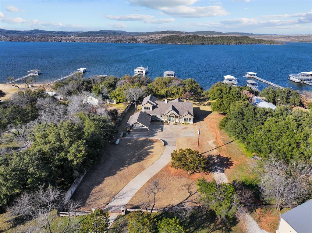 Welcome to an exquisite lakeside retreat, accessible through gated entry, where tranquility and luxury seamlessly blend into nature's splendor. Nestled on over two acres of pristine waterfront, this sanctuary is adorned with majestic oaks, offering a serene escape from the hustle and bustle. The custom-built home boasts five bedrooms and four baths, including a spacious bunk room perfect for guests. The heart of the home is a designer kitchen, featuring a sprawling island and top-of-the-line appliances. The main level hosts the primary suite, a retreat in itself with an ensuite bath and dual vanities. The living room exudes warmth with beamed wood-vaulted ceilings, adjacent to a cozy screened porch. Kids and pets will delight in the lush play yard, leading effortlessly to the sandy beach lakefront. Enjoy amenities like a carport, a 2400-square-foot boat barn for all of your lake toys, and an oversized dock with lifts. Relax on the covered lakeside patio or the open fenced area, perfect for gatherings. This property is both 1931 Deer Trail Rd and includes 1929 Fawn Circle therefore price per square foot is not accurate. 1931 deer Trail offers the home finished in 20 Dock new as of 21. 1929. Fawn is nearly an acre, dockable and houses the 2400 square-foot boat barn combined equals 2+ acres.