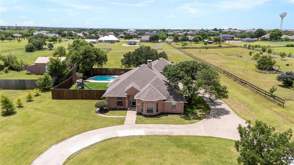 Rare opportunity to own a beautifully updated and meticulously maintained home on 1.9 acres in highly sought-after Wylie ISD with NO HOA! Offering 4 bedrooms, 3 full bathrooms, and a flexible floor plan, this property combines the space and privacy of country living with the convenience of being just minutes from downtown Wylie, local dining, shopping, and easy access to Parker Rd and 1378 Country Club. Step inside to find soaring 10-foot ceilings, crown molding, abundant natural light, and a spacious living room anchored by a cozy fireplace and custom built-ins. The fully renovated kitchen was completed in 2023 and features quartz countertops, updated appliances, double ovens, ample cabinetry, generous counter space, and beautiful views of the backyard through a wall of windows spanning the rear of the home. The oversized primary suite offers double vanities, a garden tub, separate walk-in shower, and plenty of space to unwind. Two additional bedrooms and a full bathroom are located downstairs. Upstairs, you'll find a spacious fourth bedroom with a closet and private bathroom, making it ideal as a guest suite, game room, office, media room, or second living area. This versatile space also offers private access to the walk-out balcony, where you can enjoy sweeping views of the pool and acreage below. Designed for entertaining, the backyard features a large covered patio, sparkling pool and spa, and outdoor bar area that could easily become an outdoor kitchen. Beyond the fenced backyard, enjoy an additional acre of land with endless possibilities for a shop, garden, barn, or recreational space. A circle drive and oversized parking area provide plenty of room for guests, while the two-car garage provides extra storage. Refrigerator, washer, and dryer will convey with an acceptable offer. Acreage properties in Wylie with NO HOA are hard to find. Don't miss this move-in ready home with room to entertain and enjoy country living with city convenience!