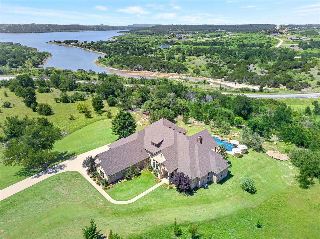 Tucked away at the end of a quiet cul de sac on more than 3 acres inside The Hills Above Possum Kingdom, this custom built single owner home offers a rare combination of privacy, space, and quality craftsmanship. With over 4,100 square feet, this property was designed for those who want room to spread out without sacrificing style or comfort.

The main living area is filled with natural light and anchored by a true chef’s kitchen built to handle everything from quiet mornings to large gatherings. Double islands provide endless workspace and seating while custom cabinetry, high end appliances, a walk in pantry, prep sink, wine refrigerator, and built in serving area make the space as functional as it is impressive.

The layout offers incredible versatility with up to five bedrooms and three private en suite setups, giving everyone their own comfortable space. The oversized primary suite features a spa style bathroom and large his & hers walk in closets, while the upstairs living area is perfect for a media room, bunk room, game room, or second lounge.

Outside, the backyard was designed for entertaining with a covered patio, fire pit, and a large resort style pool with a deep end perfect for relaxing or hosting family and friends. For added peace of mind, the home is also equipped with a whole house generator.

Located just minutes from Possum Kingdom Lake, this gated community offers upscale amenities, scenic surroundings, and convenient lake access. Whether you are searching for a full time residence or the perfect getaway, this exceptional property delivers the space, privacy, and lifestyle that make lake living unforgettable.