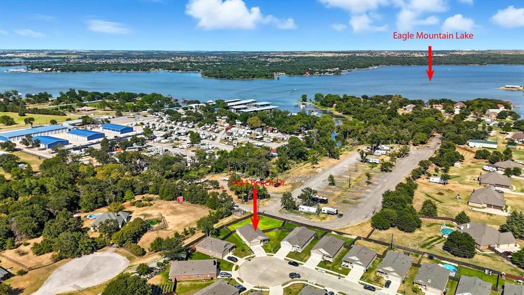 NEW ROOF!! LOW TAXES!! ***Additional incentives available, contact agent for more details***  PERFECTLY PRICED HOME! Welcome to 1404 Beach Drive, perfectly positioned by Eagle Mountain Lake and just moments from West Bay Marina and everyday conveniences! Whether you’re a boat owner, fishing enthusiast, or you just simply love lake life, this home offers the ultimate convenience with water access and recreation right outside your neighborhood. This 3-bedroom, 2-bathroom single story home sits on a private and on of the LARGEST lots in the community at the corner of a quiet cul-de-sac, giving you extra space and privacy rarely found at this price point. Upon entry to the home, you will have a covered front patio for afternoon or morning coffee and Inside, the open-concept layout seamlessly connects the kitchen, dining, and family room, creating an ideal setting for entertaining or relaxing with NO CARPET. Right off the kitchen is your direct access to the MASSIVE backyard, perfect for summer barbecues after a day on the lake, install your own private pool or create your own outdoor paradise and still have room left. This is a blank canvas where the possibilities are endless for you to do as you like. The privately situated owner’s suite features a walk-in closet and an ensuite bathroom with natural light, while two additional bedrooms offer versatility for family, guests, or a home office. A two-car garage provides ample parking and storage. Come tour this home near the water at an incredible value!