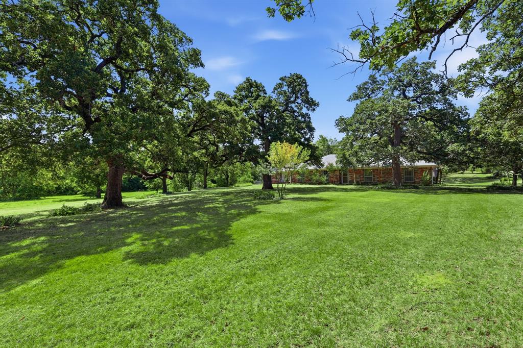 Escape the city hustle without losing the convenience of the metroplex. This charming 1,968-square-foot home sits on three sprawling acres, offering the perfect blend of wide-open space and easy accessibility. Located just moments from major highways, you can enjoy a peaceful, rural atmosphere while remaining remarkably close to top-tier dining, shopping, and major employment hubs.

The property itself is a nature lover’s dream, characterized by majestic, mature trees that provide dappled shade across the expansive lawn. Whether you’re looking to start a hobby farm, need extra storage for equipment, or want space for creative projects, the onsite barn provides incredible versatility. Inside, the three-bedroom layout feels both spacious and cozy, offering a functional footprint that’s ready for your personal touch.

This is a rare opportunity to secure a significant piece of land in a sought-after area known for its quality educational options. If you’ve been dreaming of more room to breathe and a place where you can truly unwind at the end of the day, this property delivers the lifestyle you’ve been searching for.