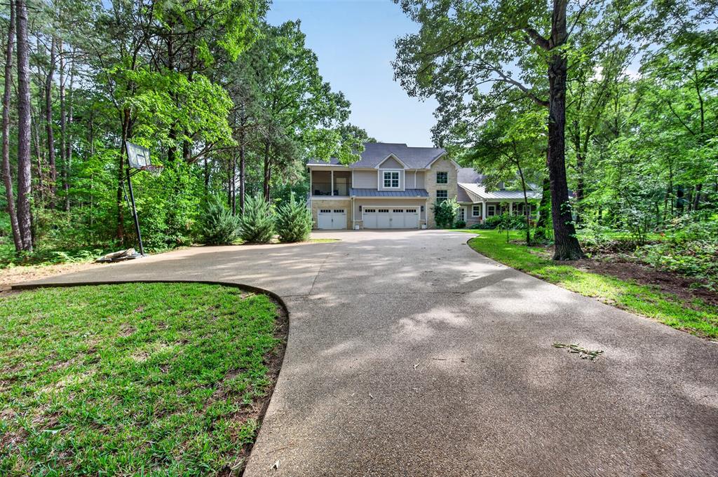 Tucked inside the gated Stonebridge Community, this custom-built 4-bedroom, 3.5-bath home sits on 9.35 wooded acres with a private pond, blending rustic charm and modern comfort. Featuring engineered wood floors, exposed beams, and a gas log fireplace, the open-concept layout includes a gourmet kitchen with gas cooktop, double ovens, and a central island. The spacious master suite offers a private bath with separate tub and shower with steam feature, a private office and open patio, while upstairs provides guest quarters with a bunk area, living space, and balcony. Outdoors, enjoy a covered patio by the heated pool, hot tub, wood-burning fireplace, grill, and scenic trails—perfect for relaxing, entertaining, and enjoying East Texas nature.