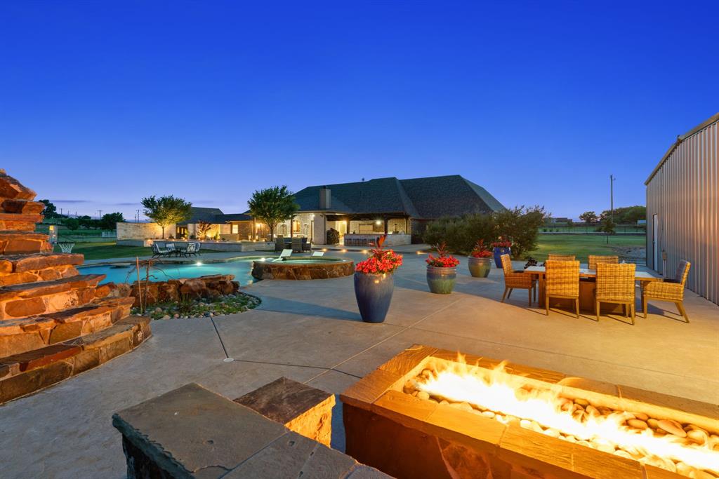 This stunning traditional, custom-built, one-story Texas estate perfectly blends classic charm with high-end luxury! Situated on 5.62 beautiful gated acres, outside city limits and close to the new Sanger High School- this timeless property with gorgeous main residence featuring an INDOOR BASKETBALL COURT, a large 3 bedroom, 1200 sf guest house and enormous 3600 sf shop that rivals any sports bar with video wall and fully equipped saloon- offers space, privacy and exceptional lifestyle features for both relaxation and entertaining! Upon entering the main residence, you will immediately fall in love! The gorgeous entryway welcomes you into the dining and formal living rooms while the open floor plan is ideal for entertaining in both the living room and chef's dream of a kitchen. Natural light pours in through the wall of windows in the front and back of the living areas flowing seamlessly into the backyard paradise! The spacious primary bedroom with spa-like primary bathroom and closet with custom built-ins, connecting to the laundry room for efficiency and ease- is separated from the 3 secondary bedrooms, each with large walk-in closets, full bath and a jack-n-jill bath, giving the utmost privacy. The entire home boasts beautiful flooring throughout and unique custom upgrades that elevate every room- from designer light fixtures, custom built-ins in the kitchen, laundry room, every walk-in closet and office to the beautifully crafted stone fireplace and everything in between! The luxury continues outside in your private paradise- a massive resort-style pool with slide, grotto and cascading waterfall and full outdoor kitchen including a smoker, pizza oven and grill are the perfect backdrop for spending your time enjoying the gorgeous Texas evenings overlooking the large stocked pond with several seating areas, a gorgeous waterwall feature, chipping mats and multiple fireplaces, you'll never want to leave! All of this plus LOW taxes with a wildlife exemption!