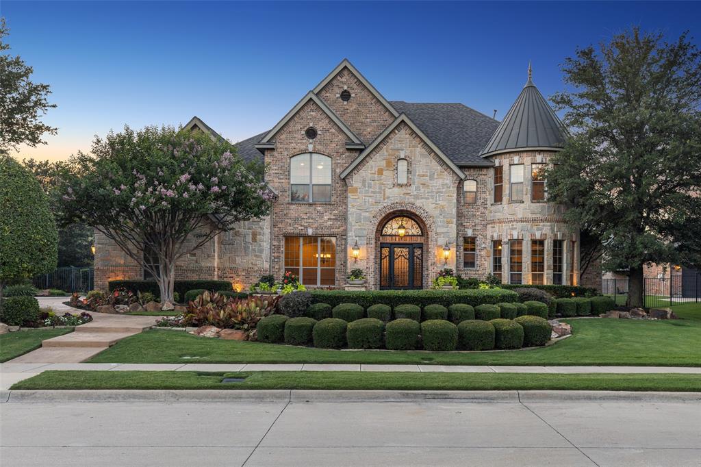 Welcome to this exceptional former model home, set on a meticulously landscaped lot in a highly sought-after neighborhood with open enrollment to Carroll ISD. From the moment you arrive, the curb appeal is undeniable, and the interiors are just as impressive. Step through a grand two-story foyer into an expansive and elegant living space, where the soaring ceilings and open layout make a striking first impression. The main level showcases extensive hand-scraped hardwood flooring and a spacious chef’s kitchen outfitted with premium finishes, adjoining a cozy wine room with stone walls and slate flooring, perfect for entertaining. This thoughtfully designed residence offers multiple living areas including a study, two dining spaces, a generous family room, and a luxurious master suite. The MASSIVE PRIMARY SUITE features an opulent spa-like bathroom with a double shower, a freestanding jetted tub, and CUSTOM DUAL CLOSETS. Upstairs, you'll find a large game room with a wet bar and an adjoining state-of-the-art media room, forming the ultimate entertainment hub. Every inch of this home reflects the elevated standards of a model property, complete with custom touches and designer upgrades throughout complete with an ELAN SMART HOME FEATURES that integrates sound, media, climate, and security throughout the house all through your smartphone. Outdoor living is equally impressive, with a covered patio, full outdoor kitchen equipped with a Viking grill, a stone fireplace, separate pergola, and travertine decking surrounding a heated pool. Whether you're hosting guests or enjoying a quiet evening at home, this backyard oasis delivers.