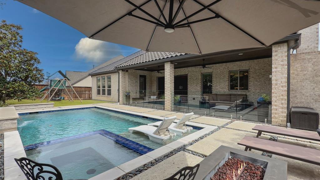 Exclusive opportunity in Walsh! Thoughtfully designed and beautifully appointed, this exceptional home blends luxury, comfort, and resort-style living in one of Walsh's most desirable locations within Aledo ISD.
Filled with natural light and designed for both everyday living and effortless entertaining, the open-concept floor plan centers around a stunning living room with custom built-ins, a fireplace, and expansive sliding glass doors that seamlessly connect the indoors to a private backyard retreat. Enjoy year-round outdoor living with a heated pool and spa, outdoor fireplace, outdoor shower, mature magnolia privacy hedge, and additional green space for pets, play, or relaxing under the Texas sky.
The chef's kitchen serves as the heart of the home, featuring a large center island, high-end appliances, abundant storage, and an effortless flow into the main living and dining spaces. A private study, formal dining room, and well-appointed guest suite with a full bath are thoughtfully positioned on the first floor, offering flexibility for work, guests, or multigenerational living.
The owner's retreat is a true sanctuary, complete with dual walk-in closets and a spa-inspired bath designed for relaxation. Upstairs, you'll find an expansive game room with wet bar, media room, additional flex living space, and two generously sized bedrooms with two full bathrooms.
Designer wallpaper, plantation shutters, elevated finishes, and a spacious three-car garage further enhance the home's sophisticated yet livable appeal.
Beyond the front door, enjoy Walsh's unmatched lifestyle amenities, including a state-of-the-art fitness center, resort-style pool, sports courts, multiple playgrounds, miles of hiking and biking trails, a private lake, dog park, neighborhood market, and on-site fuel station.
This is more than a home—it's an opportunity to experience one of the most sought-after lifestyles in North Texas.