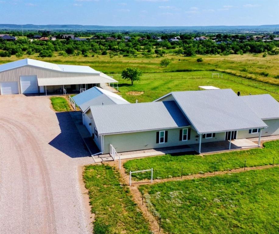 Experience the possibilities of West Texas living at 1098 E State Highway 36 in Abilene, Texas. Situated on approximately 34.81 acres outside the city limits, this rare multi structure property combines luxury, flexibility, recreation, and functionality all in one. Ideal for multi generational living, business use, livestock, entertaining, or private country living, this property offers endless potential. The main residence features 3 bedrooms and 3.5 bathrooms with spacious living areas, granite finishes, commercial grade LVT flooring, built in storage, solid core doors, and dimmable lighting throughout much of the home. The kitchen was designed for both convenience and entertaining with extensive island storage, under cabinet lighting, reverse osmosis filtration, whole house water filtration system, and a tankless style hot water system. The primary suite offers a reinforced safe room style closet, large en suite bathroom, and jetted garden tub. The approximately 50x110 warehouse style “man mansion” offers an incredible combination of living quarters and shop space complete with multiple flex rooms, loft area, office space, full kitchen, laundry area, sunroom, and two full bathrooms. The shop also features large overhead doors, RV hookups, multiple HVAC systems, and a 10,000 LB vehicle lift. Outside you’ll find an automatic gated entrance, duck pond, livestock pens with water and electric, deer blind, fire pit area, native grasses, and reseeding oats previously harvested and sold. Whitetail deer, quail, and dove regularly roam the property adding to the recreational appeal. Appliances including refrigerators, washers, and dryers can convey.