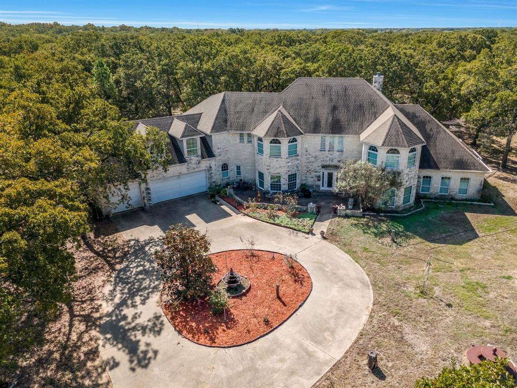 A PICTURESQUE HIDDEN GEM…tucked away in this 62+ ag-exempt acre property with a private electric gated entrance! A nature lover’s paradise…venture off through the woods to view the wildlife, including foxes and deer…An approximate 20’ deep pond stocked with bass and crappie for those who love to fish! The centerpiece of this property is a stunning two-story, custom-built Austin Stone home. The welcoming foyer has a striking floor-to-ceiling view and a unique entrance to a wine cellar under the staircase. Step into the gourmet kitchen featuring granite countertops, a center island with a cooktop, double convection ovens…a butler's pantry with a warming drawer, and an ice maker. The living room is a sanctuary of comfort, featuring tons of natural lighting and a stone wood-burning fireplace. The spacious primary suite is located on the first floor & offers a peaceful retreat with double doors leading to a private patio. The primary bath features double vanities, double walk-in closets, double laboratories, a shared oversized jetted tub, and a shower: an additional bedroom, office, and one-and-a-half bath downstairs. As you climb the winding staircase, enter a vast game room with a wet bar and media room perfect for all your family gatherings. Also on the second level is another bedroom, bath, and ensuite bed and bath. Amenities include a 1200 sq ft barn and a 600 sq ft workshop, both with electricity and water…fig, pear, and pecan trees...a fantastic chicken house with built-in nesting boxes. NO HOA! Schedule a private tour today!