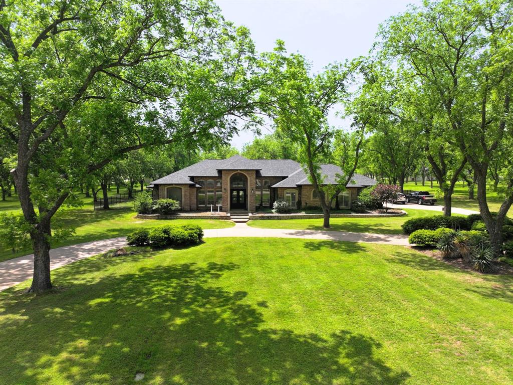 Beautifully situated on 2.3 private acres in the gated, golfing community of Pecan Plantation, this custom-built home offers an exceptional blend of space, comfort, and refined living. Mature trees, wide-open green space, and a thoughtfully designed floor plan create a property that feels both expansive and inviting.
The home features 3 bedrooms, 3 full baths, a dedicated office, and two living areas—a large open family room connected to the island kitchen for everyday living, plus a formal living room ideal for entertaining or quiet gatherings. The kitchen offers generous counter space, abundant cabinetry, and clear sightlines to the main living area and backyard.
The primary suite is a true retreat with two walk-in closets, a spacious layout, and a spa-style bath complete with a claw foot soaking tub, separate shower, and dual vanities. Secondary bedrooms are well-sized with private vanities in each room and an easy access Jack-and-Jill bath, providing comfort and privacy for family or guests.
Outdoor living shines with a sparkling pool, outdoor kitchen, and multiple patio areas perfect for relaxing, dining, and entertaining. The oversized 3-car garage offers excellent storage and room for vehicles, golf carts, or hobby space.
Located within one of Granbury’s most sought-after communities, residents enjoy access to golf, clubhouse amenities, parks, a private airstrip, 24-hour security and so much more. This property delivers the rare combination of acreage, custom construction, and resort-style amenities in a premier neighborhood.
