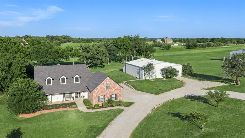 Luxury Texas aviation estate with private aircraft hangar and direct runway access, offering the ultimate fly-in lifestyle on 2.41 acres in Decatur. Located within an exclusive residential airpark community, this property allows aviation enthusiasts to keep their airplane at home and fly directly from their backyard via the community’s 2,300-foot lighted grass runway shared by only 12 property owners. This custom home offers 3,087 square feet of well designed living space with an open floorplan filled with natural light. The spacious living room features vaulted ceilings, custom built-ins, and a striking fireplace, flowing into the dining area and beautifully appointed kitchen with custom cabinetry, oversized island with Ukrainian granite, dual sinks, stainless steel appliances, large walk-in pantry, and reverse osmosis filtration system. The private primary suite features patio access, tray ceiling, and a spa-inspired bath with dual vanities, jetted tub, separate shower, and heated travertine flooring. Two additional bedrooms and bath are downstairs, while the oversized upstairs fourth bedroom includes historic wood flooring, built-ins, and ensuite bath. A mud area and oversized utility room with sink and cabinetry add functionality. Outdoor living includes a covered patio with expansive views, outdoor kitchen, stone fireplace, and a resort-style pool and spa completed in 2024. Recent updates include paint, countertops, trim, lighting, new well pump, water filtration system, new HVAC systems within the past 24 months, cell booster, and WiFi relay throughout the property. The fully insulated all-steel hangar boasts approximately 55’ x 52’, a 39’ wide by 13’ tall rolling aircraft door, epoxy flooring, full bath, climate-controlled tool room, office or man cave space, RV access door, 50-amp RV outlet, RV sewer dump, and direct taxi access to the runway. Rare opportunity for luxury living and private aviation convenience in one extraordinary Texas airpark property.