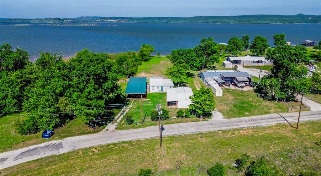 This Possum Kingdom Lake property offers a unique combination of a private beach and direct access to an expansive Brazos River Authority greenbelt, creating a wide-open feel with massive lake views that extends far beyond the lot itself—without the added property tax burden. Owned by the same family for decades, this is a choice lakefront location. The existing cabin provides a simple, usable footprint for immediate enjoyment, while the garage and guest suite offer well-maintained space for guests, storage, or weekend flexibility. For families new to PK this is where lake life really works… room to run, play, and gather, with easy access to the water and space to grow. Over time, the setting easily supports a future custom build that takes full advantage of the beach, views, and surrounding open space. Short-term rental potential adds another layer of versatility, making it possible to enjoy the property while generating income. Recent resurvey increased area of lakefront based on 1000 elevation.