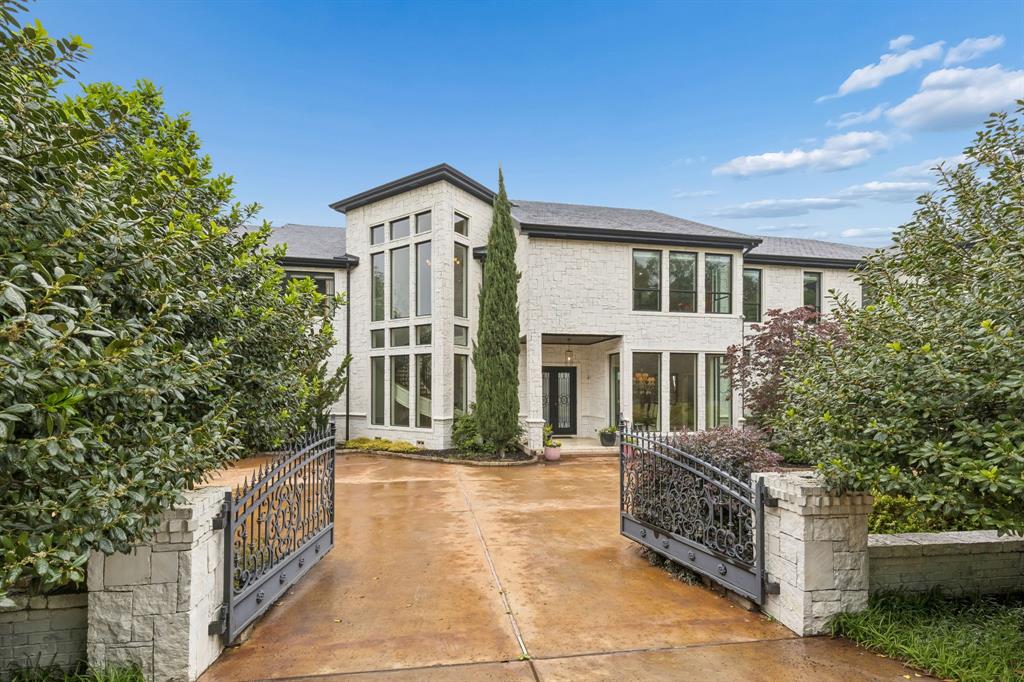Set on a beautifully landscaped acre in coveted Bluffview, this elegant estate pairs timeless architecture with refined modern comfort, creating an exceptional indoor-outdoor lifestyle. A dramatic marble entry with soaring 25-foot ceilings and a sweeping staircase sets the tone, opening to expansive, light-filled living spaces designed for both everyday living and entertaining. At the heart of the home, the chef’s kitchen is anchored by an impressive 15-by-7-foot marble island with seating for ten. Outfitted with Wolf appliances, dual dishwashers, a butler’s pantry, and a custom walk-in wine room, it flows effortlessly into the surrounding living and dining areas, all of which open to the main patio. The private primary wing offers a peaceful retreat, complete with two fireplaces, a sitting area, morning bar, and direct access to a secluded patio with a newly built gas fire feature. A spiral staircase leads to a dedicated second level with four oversized walk-in closets, while the suite also includes private laundry and a flexible bonus space nearby. Each additional bedroom is generously sized and accompanied with its own en-suite bath and walk-in closet. Upstairs, a spacious family and game room with a full kitchen is complemented by a theater room, craft space, additional laundry, and elevator access. A gorgeous, oversized office provides the ultimate work-from-home environment, featuring a built-in library, dual work areas, a central lounge with fireplace, and a private patio. Outdoors, the grounds rival a private resort, showcasing a stunning pool and spa, professional landscaping, a striking crescent-shaped gas fire feature, and a fully equipped outdoor kitchen. A 969-square-foot guest house with a bath adds flexibility for visitors or extended stays. With eight fireplaces throughout, the home is layered with warmth and ambiance. A true Bluffview lifestyle estate, thoughtfully designed for elevated living, comfort, and unforgettable entertaining.