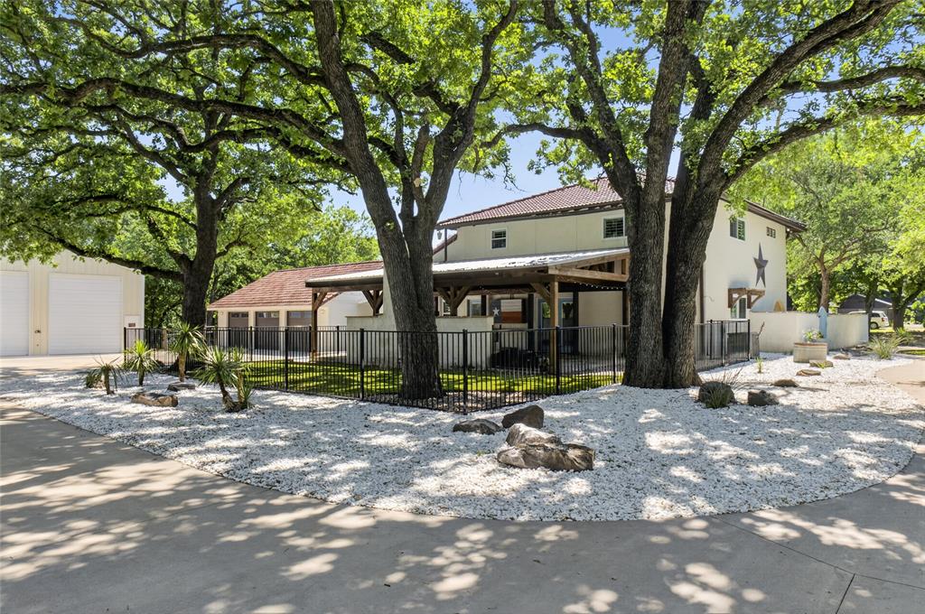 Nestled behind a private electric entry gate, this exceptional residence is situated on beautifully groomed, heavily treed 3.26 acres backing to a peaceful creek. Offering a rare combination of privacy, natural beauty, and functional living, the property delivers a true sense of retreat with mature trees, scenic views, abundant wildlife, & expansive outdoor space. One of the most remarkable features is the oversized 30x50 heated workshop — a rare, highly versatile structure designed to accommodate RV parking, car enthusiasts, hobbyists, home-based businesses, equipment storage, or substantial workspace needs. In addition, the property offers additional RV parking adjacent to the workshop, along with an oversized 3-car garage with a built-in storm shelter. Together, these amenities create unmatched functionality rarely found on acreage properties. Inside, the home features an inviting open floor plan with extensive hardwood flooring and a beautifully updated kitchen that flows seamlessly into the main living area, creating an ideal space for both everyday living and entertaining. A highly versatile downstairs flex room with a large walk-in closet and adjacent full bath offers exceptional flexibility, easily functioning as a secondary primary suite, guest suite, media room, game room, or private office. Additional bedrooms are privately located upstairs, providing separation and comfort. From the kitchen, access leads to a covered outdoor living featuring a private entertaining space with a fireplace & a dedicated dog run, making it ideal for both relaxation and functionality. The enclosed glass sunroom off the main living area adds even more versatility & can serve as a greenhouse, hobby space, seasonal retreat, or additional storage for plants & projects. This one-of-a-kind property with functional amenities, wooded creekside acreage, and outstanding workspace capabilities — all within a peaceful, private setting that feels like your own retreat. A must see!