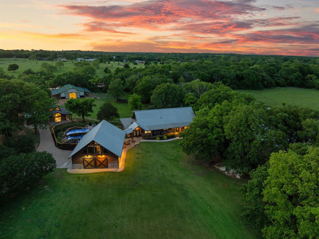 Premier 28-Acre Equestrian Estate with Covered Arena & Multiple Residences. Experience the ultimate Texas horse property at 9345 County Road 519—where function meets lifestyle across 28 ag-exempt acres designed for both serious equestrians and refined country living. This turnkey facility is anchored by an impressive 100’ x 100’ covered arena featuring sand footing over a clay base, large fan for airflow, and an attached 4-stall setup complete with instant hot water, tack room, office with heat & AC, and covered hay storage. Equine amenities continue with a separate 6-stall barn constructed with pipe and no-climb horse wire, along with dedicated storage and feed room. The property is thoughtfully laid out with cross-fenced pastures using Centaur horse fencing, multiple water sources, and productive hay fields maintaining ag exemption—ideal for both training and grazing operations. The 2,936 sq ft log main residence captures true Texas charm, featuring expansive wraparound porches overlooking a stocked pond with fountain. Inside, you’ll find two primary suites, along with a well-appointed kitchen equipped with an industrial gas stove, grill, and ovens—perfect for entertaining or large gatherings. Outdoor living is elevated with a saltwater pool, separate shallow play pool, waterfall feature, outdoor shower, and convenient indoor full bath access. For guests or multi-generational living, the property includes: A 604 sq ft log and rock guest cottage with loft and attached garage. A 724 sq ft western-themed guest house situated above a 3-car garage. Conveniently located just minutes from I-35W, you’ll enjoy quick access to nearby towns (Burleson and Mansfield), shopping, and dining while still maintaining a quiet, rural lifestyle.  This exceptional property offers the perfect balance of accessibility and private ranch living. Don't miss a rare opportunity to own a fully equipped equestrian estate in the heart of DFW.