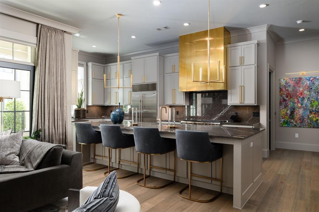 Designer-renovated luxury condo delivering effortless lock-and-leave living with refined finishes and resort-style amenities. An airy great room anchors the home with wide-plank hardwoods, a dramatic book-matched stone fireplace, and a wall of French doors that open to a covered loggia framed by classic arches, ideal for morning coffee or sunset cocktails with tranquil neighborhood and lake views.

The showpiece chef’s kitchen pairs custom double-stacked cabinetry and brass hardware with striking quartzite countertops, a full-height stone backsplash, and a sculptural metal range hood. A professional gas range, built-in refrigerator, and an oversized waterfall island with seating make everyday cooking and entertaining a breeze. Nearby, an executive study features custom built-ins, designer lighting, and an acoustic ceiling treatment for a polished work-from-home setting.

The serene primary suite showcases tailored wall paneling and a spa bath with dual vanities, a freestanding soaking tub, a large glass shower, and a separate water closet. A boutique-style walk-in closet is fully customized with LED-lit cabinetry and abundant storage. A private guest suite and an elegantly updated additional bath provide comfort for visitors.

Throughout the residence you will find designer lighting, premium wallcoverings, updated hardware, and meticulous craftsmanship that create a turnkey, magazine-worthy home. The gated community elevates daily life with a resort pool and spa, clubhouse, outdoor lounge terraces, a putting green, manicured grounds, and scenic lakeside walking paths, all moments from premier dining, shopping, and major commuter routes.