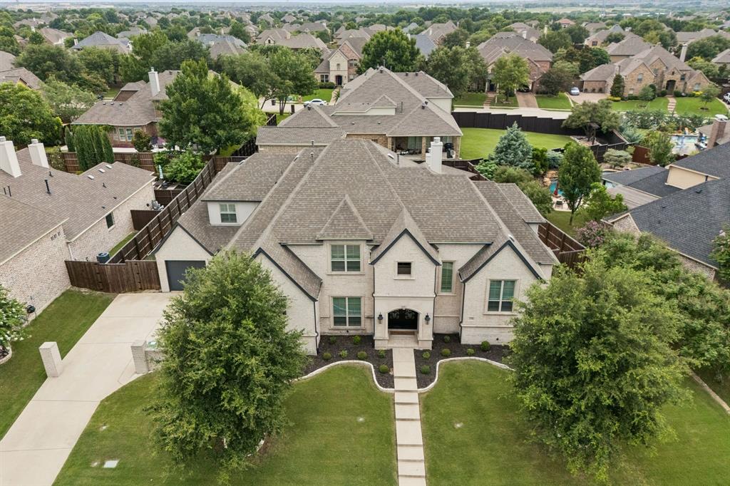 Experience luxury living in this stunning custom built Jeff Pfeifer home, completed in 2017 and ideally located in the highly acclaimed Prosper ISD with convenient access to the Dallas North Tollway. Perfectly situated on a desirable north-facing lot in Lakes of La Cima, this meticulously maintained home offers an exceptional blend of elegance, comfort, and thoughtful design.A grand entry through custom iron double doors sets the tone for the impressive interior. The carefully designed floor plan flows seamlessly and features two dining areas, a spectacular two-story great room with cathedral ceilings, exposed wood beams, and a stone wood-burning fireplace with gas logs. The chef's kitchen is truly the heart of the home, showcasing premium appliances, a built-in oversized refrigerator, freezer, two walk in pantries, and abundant prep and storage space.The first floor also includes a luxurious primary suite with direct pool access, a private guest suite (or second primary suite), and a media room. Midway up the staircase is a dedicated home office complete with a walk-in storage closet. Much of the home is wired for surround sound, enhancing both everyday living and entertaining.Upstairs you'll find three spacious secondary bedrooms, two with ensuite baths, plus an additional full bath serving the third bedroom and game room.The backyard is nothing short of spectacular—a true resort-style retreat designed for year-round entertaining. Enjoy the 50-foot heated pool with attached spa, two waterfalls plus a dramatic rain waterfall, a swim-up bar with seating, and a sunken covered outdoor kitchen featuring a built-in pellet grill, bar sink, and under-counter refrigerator. A spacious covered patio with a wood-burning fireplace, wired for surround sound and a separate fire pit complete this incredible outdoor oasis.Offering 5 bedrooms, 5 full baths, 1 half bath, a 3-car garage, game room, media, exceptional chefs kitchen, this extraordinary home truly has it all.