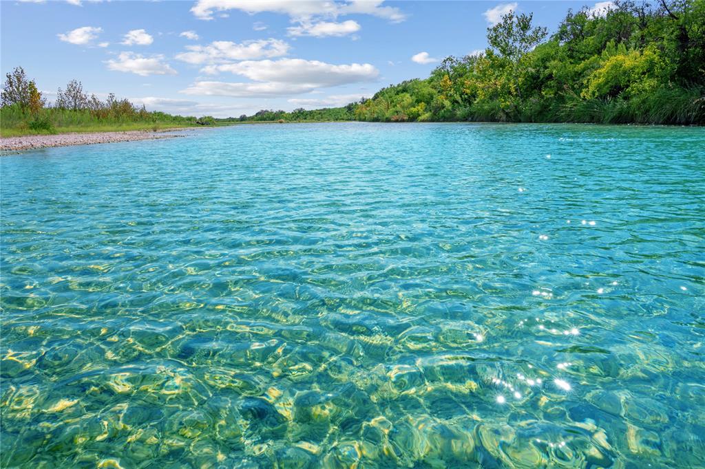 Nueces River Ranch is an extraordinary 7,530-acre legacy property set deep in the wild heart of the Edwards Plateau, a rare oppty to own a ranch of this scale in today’s market. For those seeking even more, an additional 960 ac is avail, featuring a ranch home, like-new shop, cattle pens, &  extra half mile of private Nueces River frontage. Together, the combined offering totals over 8,490 acres, delivering expanded river access & turnkey improvements. The main tract boasts approx half a mile of private frontage along the crystal-clear Nueces River, forming a serene western boundary & creating an oasis for swimming, fishing, kayaking, & quiet retreat. Anglers will appreciate strong populations of Guadalupe bass, largemouth bass, sunfish, & catfish. Beyond the river, the ranch is well-watered with 2 reliable wells, multiple watering holes, & an extensive network of buried lines supplied by 3 cisterns ensuring consistent water for both wildlife and livestock. The landscape is richly diverse and undeniably beautiful. Towering live oaks, mesquite, & sycamore trees dot the terrain, while springtime brings vibrant blooms of TX bluebonnets, Engelmann daisies, Maximilian sunflowers. Spanning roughly 5 miles by 5 miles, the ranch transitions from rolling plateaus to rugged canyons carved by seasonal creeks. Elevations range from 1,160 ft to 1,664 ft summit, offering sweeping 360-degree views of the Sycamore Mtn. Range & surrounding countryside. Accessibility is exceptional, with maintained main roads & an extensive network of UTV trails traversing the property. Perimeter barbed wire fencing defines the boundaries, and electricity has been extended into the ranch, providing a strong foundation for future improvements. Located just 20 mi from both Uvalde & Camp Wood, the ranch strikes a rare balance between privacy & convenience. Nueces River Ranch is more than land it’s a generational holding offering unmatched scale, natural beauty, & the enduring promise of a Texas legacy.