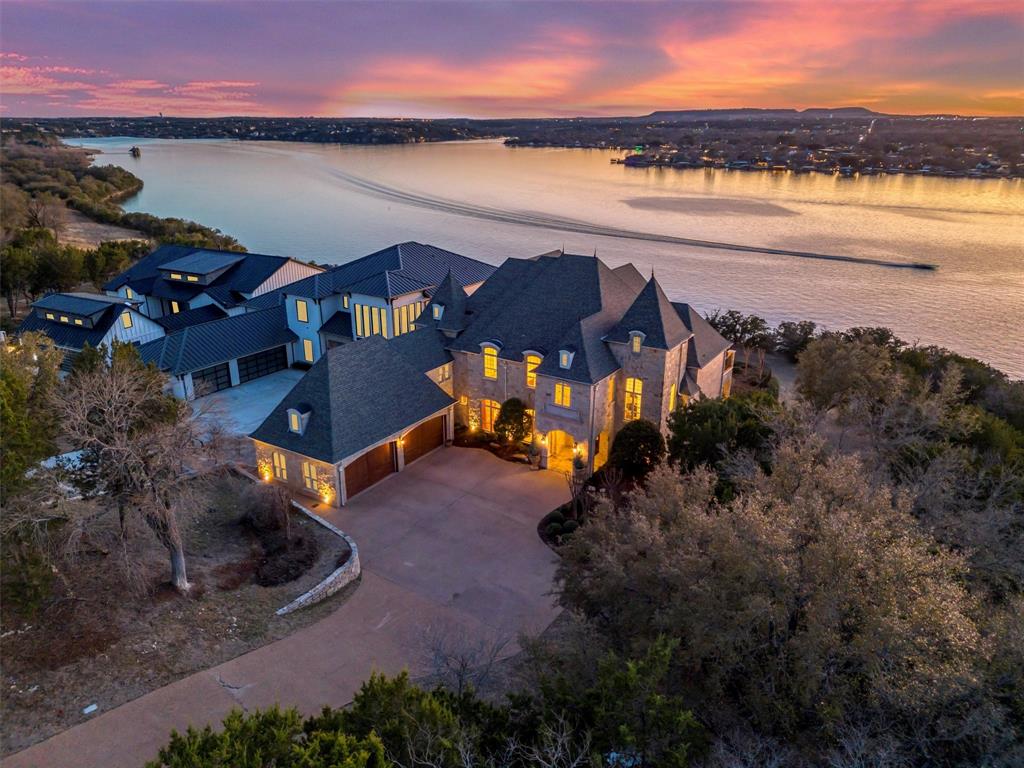 Owner Financing Available 2% UNDER PRIME with 25% down with approved credit! Step into a slice of French luxury right in the heart of Grand Harbor, where timeless elegance meets lakefront living. This 6,619 sqft masterpiece sits proudly on 90 feet of prime waterfront along one of Lake Granbury's deepest channels, complete with a 14-ft retaining wall—ensuring not only stunning views but also unmatched lake access.
Inside, you’ll find 5 spacious bedrooms, each with its own en-suite, plus 2 additional powder rooms (one upstairs and one down). The master suite is a true sanctuary, featuring heated floors in the spa-like bath, a steam shower, and even a coffee bar to elevate your morning routine. Everything is elevated in this home including a high end custom trim package, solid wood 8-ft doors, 14 varieties of granite—because details matter.
Entertain in style with three cast stone fireplaces (sealed propane and vented), an oversized media room  on the second story with a kitchen, and a fitness room. The second-story deck offers panoramic lake views, while the 800 sqft floored attic and climate-controlled AV room provide practical luxury. Your 4-car garage ensures space for all your toys.
An office with breathtaking lake views makes working from home a dream, and the gourmet kitchen is ready for your culinary adventures. This is more than a home—it's a lifestyle. Don’t miss this rare opportunity to own one of the finest homes in Granbury. 
Ready to make it yours? The lake is calling!