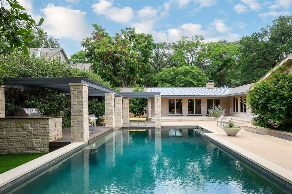 Palm Springs-inspired mid-century modern retreat in highly sought-after Merriman Park Estates, one of East Dallas’ most desirable neighborhoods. Designed for seamless indoor-outdoor living, this distinctive home offers an expansive open floor plan with double living and dining area framed by oversized windows that flood the interiors with natural light and connect beautifully to resort-style outdoor spaces. The chef’s kitchen features a gas cooktop, double ovens, an integrated Sub-Zero refrigerator, abundant cabinetry, and generous prep surfaces. Natural hardwood floors, fresh interior paint, and clean architectural lines create a sophisticated yet welcoming atmosphere throughout. Step outside to a private backyard oasis designed for luxury entertaining, featuring a sparkling pool and spa, mosquito-controlled lounge and dining areas, an outdoor grilling space, mature shade trees, and dramatic landscape lighting. The thoughtful split-bedroom layout offers ultimate privacy. The spacious primary suite serves as a tranquil retreat with dual showers, a soaking tub, and a large walk-in closet. Three additional bedrooms and a generous secondary bath with a separate shower and soaking tub provide comfortable accommodation for family and guests. Premium extras include a whole-home generator (powers the residence, pool, and spa), two fireplaces, extensive garage storage, and a custom front deck. Ideally located near White Rock Lake, White Rock Trail,Parks, shopping, and dining, this turnkey luxury home offers a rare Palm Springs sanctuary in Dallas.