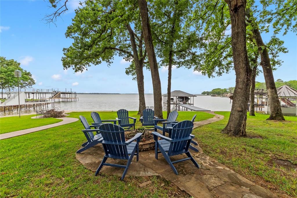 Positioned on open water in the sought-after Deer Island community, this fully remodeled home offers sunset views and a cozy feel nestled under a canopy of mature oak trees. Relax on the spacious flagstone patio overlooking the over quarter-acre lot, where a fire pit creates an inviting lakeside setting. A stone walkway leads down to the boathouse, and a circle driveway provides ample parking for family and guests.

Inside, vaulted ceilings and floor-to-ceiling windows define the open living, dining, and kitchen area, bringing in natural light and keeping the water in view throughout the main living space. The kitchen features quartz countertops, custom cabinetry with abundant storage, a large island for gathering, and stainless steel appliances, complemented by a beverage center just off the back door for easy access to the outdoor living area. The living area is centered around a wood-burning fireplace, with crown molding, recessed lighting, and durable white oak-look flooring carried throughout.

The layout includes three bedrooms, with two located on the main level along with a full bath that also functions as an en suite with guest access. The upstairs primary suite offers a more private retreat with its own en suite bath and private balcony. Bathrooms have been beautifully updated with tiled showers, glass enclosures, quartz countertops, and modern stainless fixtures.

Approximately 70 feet of platted waterfront on an over quarter-acre lot features a steel retaining wall, lake pump sprinkler system, and St. Augustine grass. The boathouse offers a wide walkway, covered boat slip, dual PWC lift, plus an additional PWC lift on the side, along with lake stairs for easy access to the water. A large storage building with a roll-up door on the water side provides excellent space for water toys and outdoor furniture.