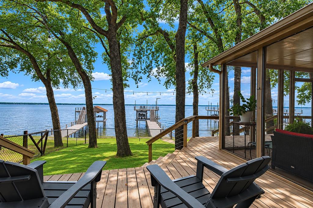 Stunning waterfront retreat offering breathtaking sunset views and the perfect setting for relaxing lakeside living. This well-maintained home features 3 bedrooms and 2 bathrooms with a spacious living room showcasing vaulted ceilings, expansive windows, and a beautiful stone wood-burning fireplace. The kitchen offers granite countertops, a breakfast bar, and built-in oven and microwave, making it ideal for entertaining and everyday living. Step outside to enjoy the screened-in covered patio that opens onto an expansive deck overlooking peaceful water views. The property is being offered furnished, making it ready to enjoy this summer season.

The backyard is fenced and beautifully landscaped with mature trees providing plenty of shade, lush green grass, and a sprinkler system pumped directly from the lake. Seller has also made significant drainage improvements to the property, contributing to the well-maintained grounds and outdoor enjoyment. Additional exterior features include a carport with attached storage and additional parking available at the street.

The property also includes an impressive 2-story boathouse featuring a custom boat cradle, automatic boat cover, durable aluminum decking on the party deck, lake stairs for easy water access, personal water craft lift, and excellent deep water even during lower lake levels. Conveniently located close to shopping, restaurants, and all that Gun Barrel City has to offer, this home is the perfect combination of comfort, recreation, and lakeside living. An added bonus located in a voluntary HOA with community park with covered pavilion for events, and children’s play scape. HOA does not restrict short-term rentals. Permitting required through Gun Barrel City for Short Term Rentals.
