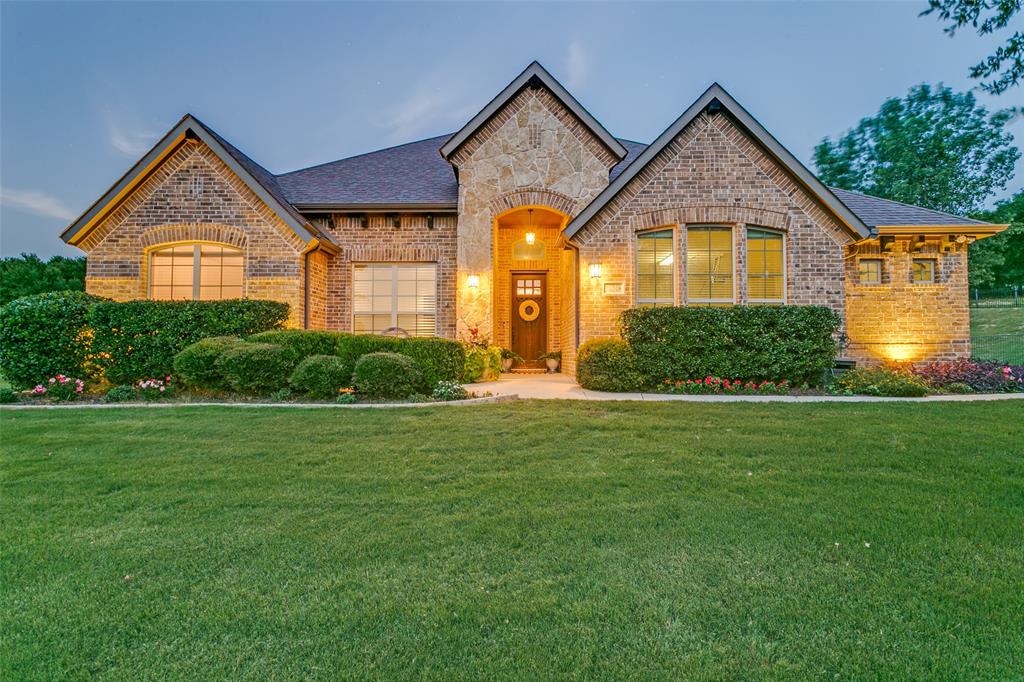 Relish in the tranquil evenings and breathtaking sunsets from the front patio of this home in Mustang Pointe. Upon entry to this exceptional home, one is greeted with a stunning entry with craftsman doorway casement, transom window, and crown molding accentuating the high ceiling. An office to the left includes a closet and a barn door for privacy affording the room to many different uses. Hand-scraped wood floors lead to the open living, kitchen, and dining areas. These areas enjoy a plethora of natural light from an expansive wall of windows looking out over the 1-acre lot. The focus point of the living room is the wood burning fireplace flanked by alcoves waiting for the new owner’s inspiration to transform them into functional and stylish areas for storage, displaying favorite art pieces, or reading nooks. Enjoy the custom transition of an arched wall to the kitchen and dining areas. Granite countertops compliment the sophisticated cabinetry and oversized island of the kitchen. The kitchen affords an abundance of storage that includes a corner panty. An oversized dining area allows space for a buffet or sideboard. The primary bedroom is separated from the secondary bedrooms and has room for a sitting area. A spacious primary bathroom has dual sinks, separate tub, and walk-in shower with wall and rain shower heads. Two secondary bedrooms share a hall bathroom. A bonus room upstairs enjoys a half bath. It could serve as a guest room, media room or family room. The generous-sized utility room includes storage. Outside a large wrought iron fenced backyard offers a plethora of opportunities. The covered patio makes an ideal outdoor retreat. A two-car garage and one-car garage are located on the side of the home with an extended concrete driveway for additional parking. Located off FM-1187 this enjoys quick access to Hwy. 377, Chisolm Trail Parkway, Benbrook Lake, retail shopping and entertainment. Backyard play set conveys with home.