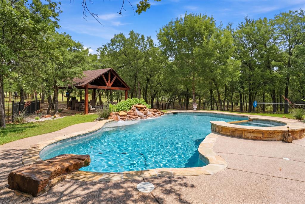 Experience luxury country living at its finest in a gated community nestled on 3.39 breathtaking acres filled with mature towering trees, inground pool and spa, gazebo, outdoor shop, you name this one has it... This exceptional property offers the perfect blend of elegancy, privacy and functionality in the highly sought after Azle ISD. With 3503 sf of thoughtfully designed living space, this stunning home is tucked away in a serene setting that feels like your own private retreat. Inside, you will find a recently remodeled kitchen, 4 spacious bedrooms, a dedicated office, formal dining room, media room, and an ideal floorplan designed for both everyday living and entertaining. The luxurious primary suite is conveniently located on the first floor with a warm and cozy fireplace to enjoy and offers a peaceful escape with a spa inspired comfort. A private secondary bedroom along with a full bathroom could be used as a mother in law suite and adds flexibility for guests or multigenerational living. The kitchen has been recently remodeled, and the countertops are an upscale granite, stainless steel appliances, spacious pantry and eating area. All of the five spacious bedrooms have walk in closets. Upstairs features the remaining secondary oversized bedrooms, media room, and an ample area for lap top space and built in desks to game at or work on homework.Adding even more value is the insulated shop, ideal for hobbies, storage, or additional workspace. A gorgeous high end, inground peerless pebble pool and spa with water features and even an adorable bridge that adds charm and character. House has been designed for high efficiency with solar backed roof boards,radiant barrier decking,and all new high efficiency windows.  Every detail of this property was designed to offer comfort, privacy, and refined Texas living. Rarely does a property combine luxury, acreage, mature trees, pool, shop, gazebo, and an exceptional one owner custom built home all in one remarkable package.
