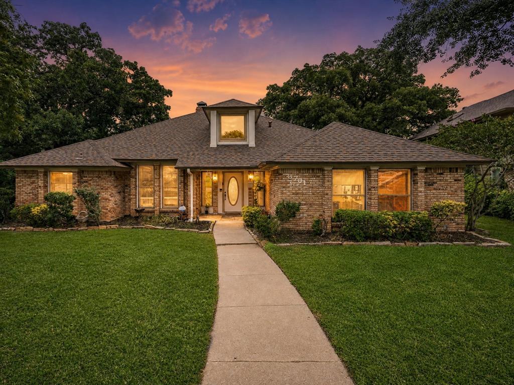Positioned on a beautifully landscaped corner homesite, this single-story brick residence offers an adaptable floor plan with several distinct areas for relaxing, working, and entertaining. Hardwood floors bring warmth to the primary gathering spaces, while vaulted architectural elements, detailed woodwork, and generous windows enhance the home’s character and natural light.

A brick-hearth gas fireplace anchors the main living area, which also includes display shelving and a built-in wet bar. The second living room provides another impressive fireplace, decorative wood ceiling accents, and ample space for media, games, or conversation. Separate formal living and dining rooms add further flexibility for entertaining, office use, or other personalized needs.

Granite surfaces, abundant cabinetry, stainless steel appliances, a breakfast bar, and exposed wood detailing along the vaulted ceiling define the eat-in kitchen. The primary bedroom includes a private bathroom with two vanities, a separate shower, soaking tub, walk-in closet, and a comfortable retreat-like atmosphere. One secondary bedroom is thoughtfully separated from the others, while two additional bedrooms offer space for guests, family, or a dedicated workspace.

The outdoor areas are designed for both recreation and hosting. An expansive elevated covered deck creates room for grilling, dining, and lounging. Below, the backyard features an in-ground swimming pool, spacious concrete decking, stone retaining walls, and a covered cabana-style sitting area. A Bose surround-sound system located in the secondary living room will remain with the home.

Served by Arlington ISD & zoned for Martin High School, the property offers convenient proximity to I-20, retail, restaurants, and everyday services. Nearby Lake Arlington and Bowman Springs Park provide access to fishing, boating, picnicking & waterfront recreation. AT&T Stadium, Globe Life Field, Six Flags Over Texas, Hurricane Harbor, are also close by.