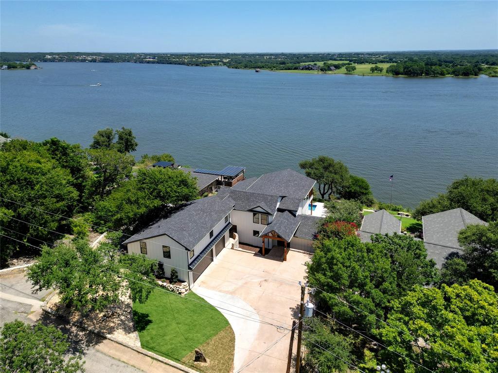 New Price Improvement — Rare bluff-top luxury lakefront retreat on the main body of Lake Granbury with panoramic views, pool and spa, private dock, and fully renovated interiors.

Perched high above the main body of Lake Granbury, this fully renovated 5-bedroom, 4.5-bath waterfront retreat offers one of the most unforgettable lake settings in Granbury. With approximately 100 feet of elevated shoreline, dramatic bluff-top positioning, and wide-open, unobstructed water views, this home delivers a lakefront experience that is difficult to duplicate.

Inside, the home has been thoughtfully reimagined with a bright, open layout designed for gathering, relaxing, and taking in the view. Expansive windows fill the living spaces with natural light and frame panoramic lake views from nearly every major room. The designer kitchen features quartzite countertops, custom cabinetry, double ovens, and an oversized statement island perfect for entertaining family and friends.

The spacious living area flows seamlessly to the outdoor patio, pool, and spa, creating a true indoor-outdoor resort feel. With 5 bedrooms plus a game room, the home offers exceptional flexibility for large families, guests, and multi-family stays. The property also has a proven track record as a successful short-term rental, offering flexibility as a full-time residence, luxury weekend escape, or income-producing lake retreat when not in personal use.

Outside, enjoy a covered patio, sparkling pool and spa, expansive outdoor entertaining areas, and a private boat dock, all positioned against a breathtaking main-body backdrop. The elevated setting provides rare privacy, dramatic views, and a perspective of Lake Granbury that most waterfront homes simply cannot offer.

From its elevated setting and unforgettable views to its resort-style outdoor living and proven rental appeal, this is a rare Lake Granbury property designed to be enjoyed, shared, and remembered.