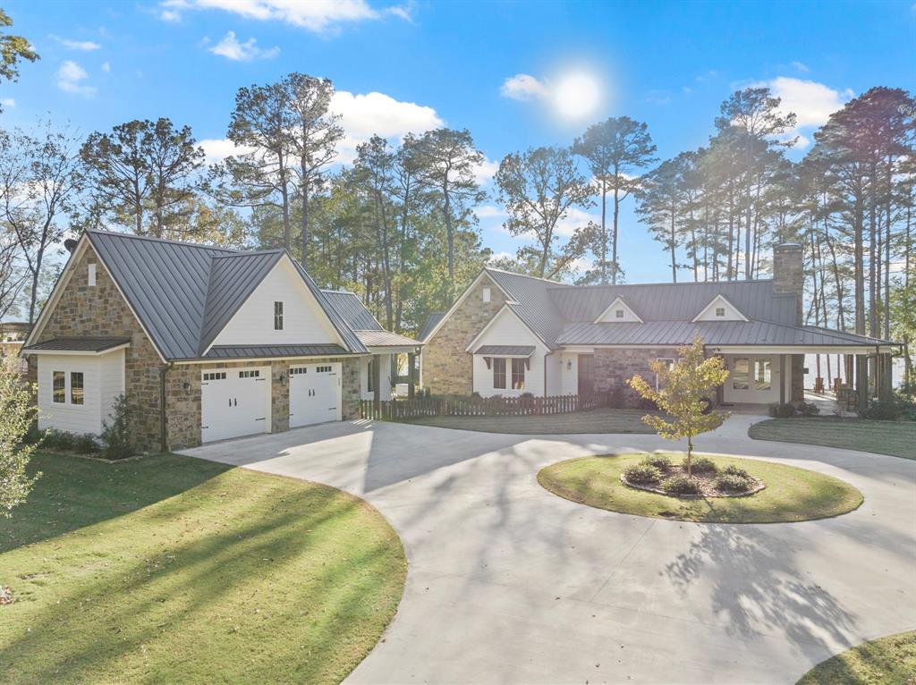 Discover your dream retreat in the pristine Lost Pines subdivision, where this stunning lakefront property spans nearly 1.5acres and boasts over 3,400 sq ft of luxurious living space. Built in 2023, this open-concept residence features beautiful engineered hardwood flooring, a striking stone fireplace, and two expansive kitchen islands equipped with top-of-the-line appliances. The lavish primary en-suite offers a serene oasis with breathtaking views featuring dual sinks, a soaking tub, a tile shower, and a spacious walk-in closet. Additional highlights include a detached guest house, a boathouse with slips for two jet skis and a ski boat, and a vast porch perfect for enjoying spectacular sunsets by the water's edge. Combining luxury, comfort, and nature's beauty, this home is not just a place to live; it's a lifestyle waiting to be embraced.