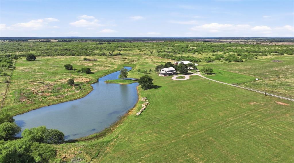 Located in northwest Jack County just east of Antelope, this 330 plus acre ranch offers a combination of improved pasture, water features, and functional improvements suited for ranching, recreation, or multi generational living.

The main residence is a 1,671 square foot two bedroom, two bath story and a half log cabin style home. The interior includes a full kitchen, wood burning stove, and an eat in dining area. A wrap around deck overlooks a scenic 2 acre lake positioned near the home. In addition to the primary residence, the property includes a 60 x 40 barndominium. The structure contains approximately 1,920 square feet of living space and 1,440 square feet of insulated shop and warehouse space. The first floor features an open concept layout with kitchen, living area, restroom, and office. Upstairs are two bedrooms, a workspace and office area, and access to a balcony overlooking the lake.

The main home, barndominium, and lake are situated within a pipe fenced compound of approximately 25 acres. Improvements include working pens, cross fencing, and an additional stock tank. The ranch has significant paved frontage along FM 174 with multiple gated entrances. An additional 48 acres lie across FM 175, with Bowen Loop forming the north and west boundaries.

Water is supplied by a well producing approximately 13 gallons per minute at around 145 feet. Both residences are serviced by the well. Electric service is provided by J A C Electric Cooperative. An agricultural tax exemption is currently in place.

Seller intends to convey all owned mineral rights, believed to be approx. one third of the mineral estate. No active mineral production is present on the property.

The land features sandy loam soils, gently sloping terrain, and a mix of open areas and wildlife habitat. Native game in the area includes whitetail deer, turkey, and hogs. This property is well suited for buyers seeking a functional ranch with established improvements already in place.