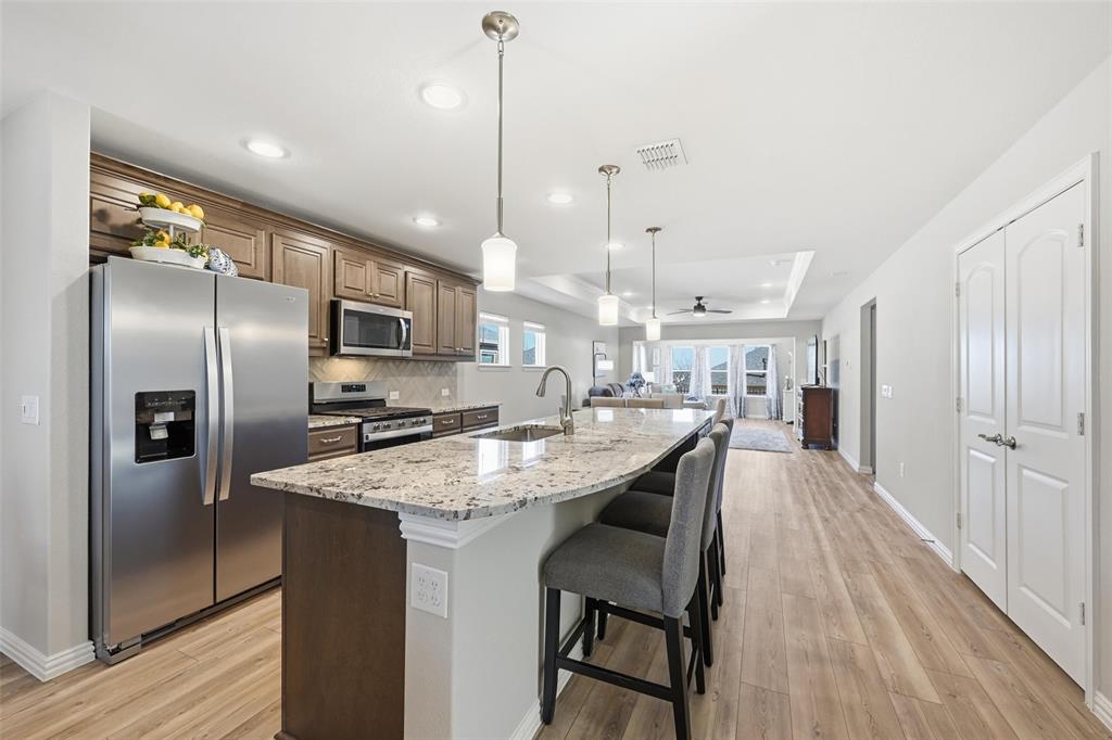Move-in ready and perfectly positioned in Del Webb, this home offers the best of active adult living with a short walk from pickleball courts, resort-style pool, clubhouse, and fitness center. The Steel Creek floorplan is designed for both comfort and connection, the open floor plan centers around a stunning kitchen with a massive granite island, stainless steel appliances, custom pull-out drawers, and breakfast bar seating—ideal for everyday living or entertaining. The kitchen flows seamlessly into the living room and sunroom, creating bright, inviting spaces to relax or host guests. Two dining areas provide flexibility, with the front dining space easily doubling as a home office. Tray ceilings and abundant recessed lighting add a polished touch throughout. Enjoy morning coffee on the charming front porch or unwind on the covered back patio. Two spacious bedrooms include a private primary suite featuring dual sinks, a walk-in closet, linen storage, and a glass-framed shower. Low-maintenance living meets an active, social lifestyle in this exceptional Del Webb home.