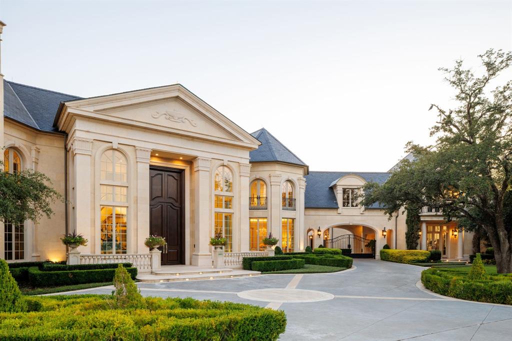 Welcome to 10617 Bridge Hollow — a masterwork of architecture, integrity + serenity. Tucked in the exclusive Creeks of Preston Hollow, this residence rests on a private lot where 2 creeks wind through lush, tree-lined banks. It stands as a rare union of natural beauty + enduring craftsmanship. This 2018 custom home spans 1.44 AC + is framed entirely in steel — a $500K investment ensuring lifelong stability. 130+ piers run deep into Austin chalk, forming a foundation that’s a feat of engineering. The timeless design features a Syrian limestone façade + slate roof built for a century of endurance. Hand-carved fireplaces, steel gutters + integrated drainage reveal an obsession w permanence + precision. Step through the 20-ft African mahogany door + the home unfolds in a play of light + volume. Ceilings soar to 25 ft in the entry + 17 in the living room, framed by windows overlooking nature. Each space exudes quiet grandeur — oak + limestone floors, bespoke chandeliers + refined proportions. The kitchen is a sculptural statement in quartzite, onyx + brass, backed by a scullery for effortless entertaining. The Control4 system unites lighting, sound + security. The 1st-flr owner’s suite is a private sanctuary w heated marble floors, automated shades, massive closets + a massage-exercise room open to a serene backyard. A library w built-ins + a custom fish tank adds sophistication + warmth. A spacious guest suite rounds out the main level. Upstairs, 4 guest suites w private baths overlook treetops + water views, while a glass staircase from Australia arcs through the home like sculpture. A game room offers flexible space for entertaining + a basement wine cellar provides abundant storage for collectors. A resort-style backyard, inspired by Palm Springs, features a tranquil pool, turfed lawn + elegant lighting — a landscape of privacy + peace. This residence is a testament to enduring design — built for those who value substance, beauty + permanence in equal measure.