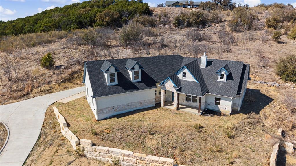 Discover your own slice of Texas paradise, where wide-open skies seem to go on forever and the stars light up the night in unforgettable fashion. Located in the highly desirable community of The Hills Above Possum Kingdom, this beautiful home combines peaceful surroundings with modern-day comfort. From the moment you walk through the door, you’re greeted with warmth and natural light. Large windows showcase breathtaking views that shift beautifully throughout the year, bringing the outdoors in. Picture slow mornings on the patio with a cup of coffee in hand, watching the hills come alive, or evenings spent gathered with friends beneath the vast Texas sky. Designed with connection in mind, the open living space flows seamlessly, making entertaining both easy and enjoyable. The kitchen is thoughtfully appointed—equally suited for everyday meals and special occasions—offering the perfect setting for creating lasting memories. At the end of the day, escape to your own private retreat, a space created for comfort and rest. Step outside and imagine the possibilities. There’s plenty of room to craft your ideal outdoor escape—whether that means cozy firepit conversations, peaceful sunset views, or simply soaking in the natural beauty that surrounds you. Residents of this exceptional community enjoy outstanding amenities, including lake access, a resort-style pool, a fitness center, and expansive areas to explore and unwind. Whether you’re searching for a weekend getaway or a full-time residence, this home offers more than a place to live—it offers a way of life. Come experience it firsthand. Your lake escape awaits.