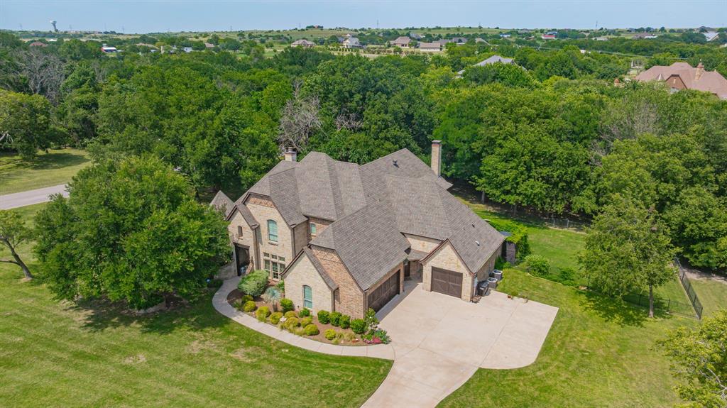Welcome to this award-winning estate, voted Best of Show in the 2008 Parade of Homes and crafted by Parker County's celebrated builder John Askew. Located in Aledo ISD, this home is tucked inside a very private gated community of just 41 estate-sized homes, complete with freshly resurfaced streets and a private, stocked neighborhood lake reserved for homeowners, this residence offers a rare blend of luxury, privacy, and natural beauty.

Set on a 1.43-acre heavily treed corner lot bordered by a flowing creek, the home makes an unforgettable first impression. A wall of massive windows greets you upon entry, framing a dramatic view of the lagoon-like pool and park-like shade trees beyond.

Inside, custom hand-scraped oak floors run throughout much of the first story, while towering high-beamed ceilings crown the entry, office, master suite, and living areas. High-end wall textures and finishes, custom draperies, and room-darkening shades in the bedrooms reflect the home's attention to detail at every turn. Two fireplaces add warmth and character, and a Juliet balcony lends a touch of elegance.

The huge master suite is a true retreat, featuring a jetted, spa-like soaking tub. Car enthusiasts will appreciate the NASCAR-styled garage floor finish, and the entire backyard is enclosed by handsome black iron fencing and gates.

Recent updates bring peace of mind, including all three HVAC units, both hot water heaters, the kitchen stovetop, dishwasher, well pump, and an architectural-grade roof, all recently replaced.

Privacy, craftsmanship, and timeless design come together in this exceptional Parker County estate. Schedule your private showing today.