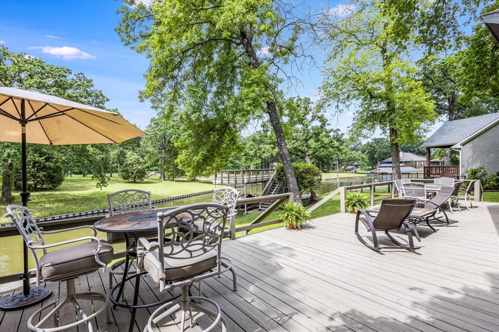 Looking for the perfect lake getaway for the weekend or that forever home to retire in and live your best life? Look no further! This recently updated lake house is located in the desirable close knit gated neighborhood of Beachwood Estates and offers 2 living rooms, 3 bedrooms and 2 full baths and is beautifully maintained. There is 109 ft. of protected water frontage with steel seawall, fishing pier and a boathouse with 2 PWC lifts and an upper spacious party deck. The open concept floorplan is perfect for entertaining. Living room has a wall of window to look out at the lake, landscaped backyard and fireplace with gas logs and remote. The updated kitchen features SS appliances and tile countertops and oversized island. Find beauty in the details of this home from spacious bedrooms, large tiled shower in remodeled primary bathroom, smart home equipment and outdoor storage closet for your lawn equipment and lake toys. It's the perfect place to have your friends and family over for a day of floating, fishing and cooking out on your back deck. The subdivision has a community pool, clubhouse, playground, boat launch, pickleball and tennis courts. All you need is your swimsuit and flip flops to start making fun lake memories! Electronics, furnishings and watercraft available for purchase.